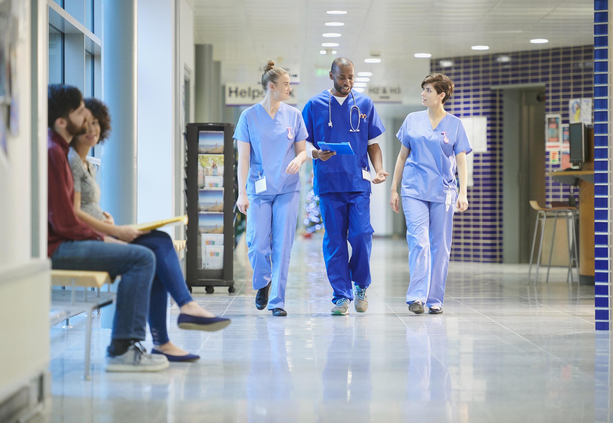 Nurses having a conversation walking through hospital corridors