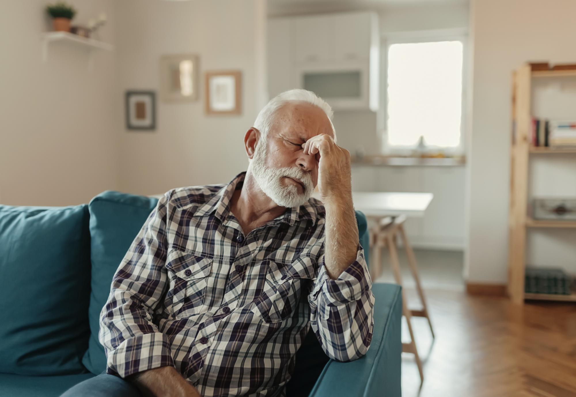 Older man holding his head with a migraine