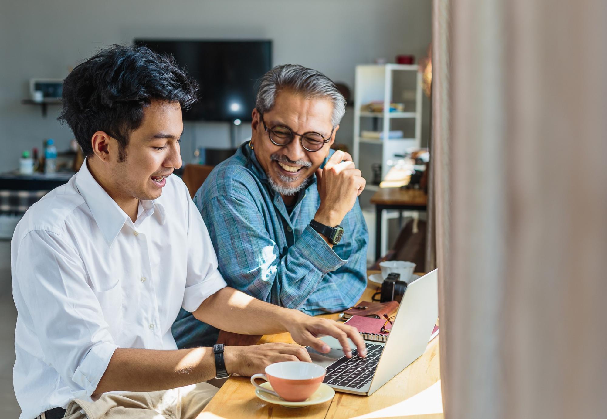 Asian father and son chatting at a laptop