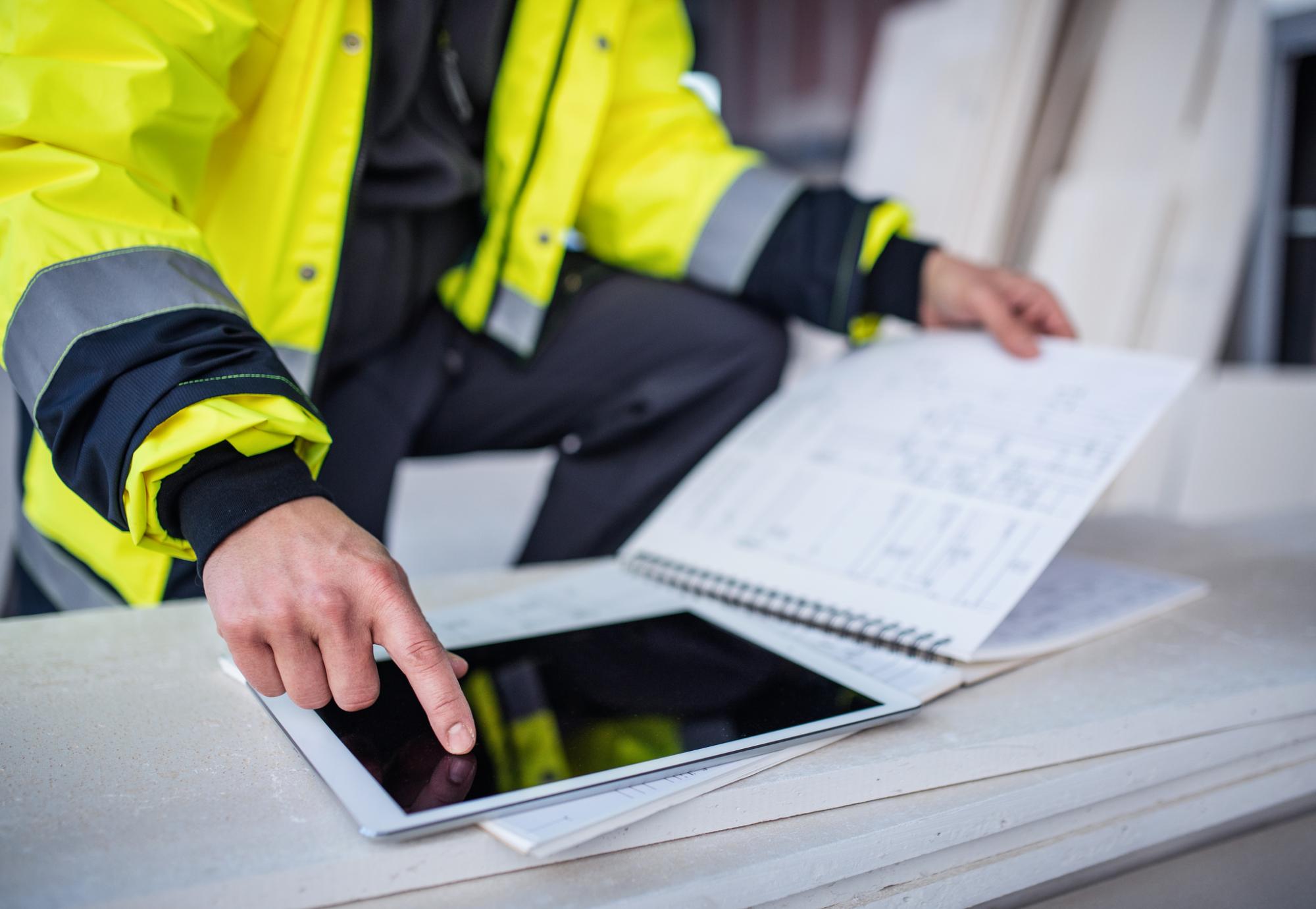 An engineer checks between notes in a notepad and on a tablet PC