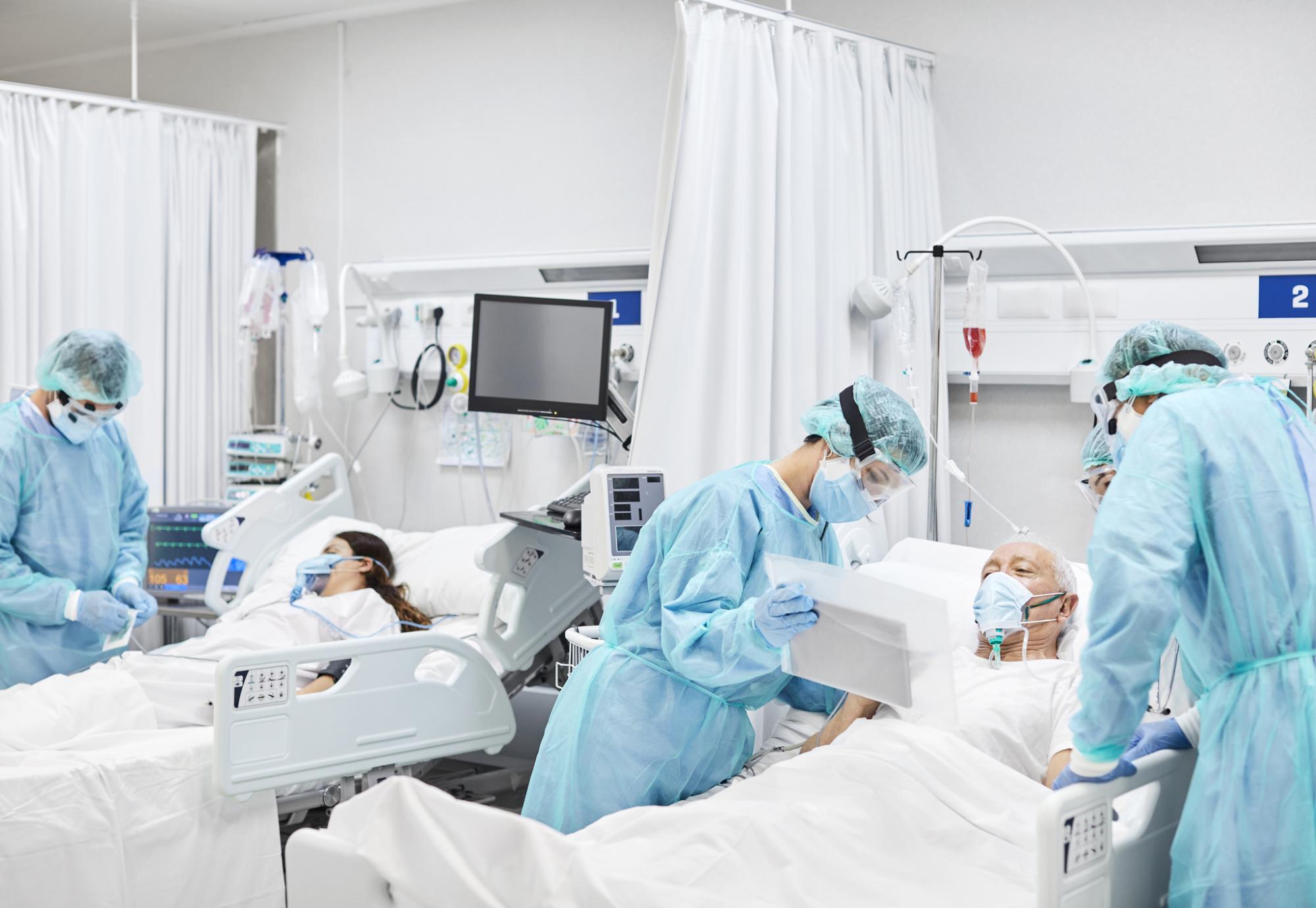 Health professionals in PPE treat patients in a hospital ward