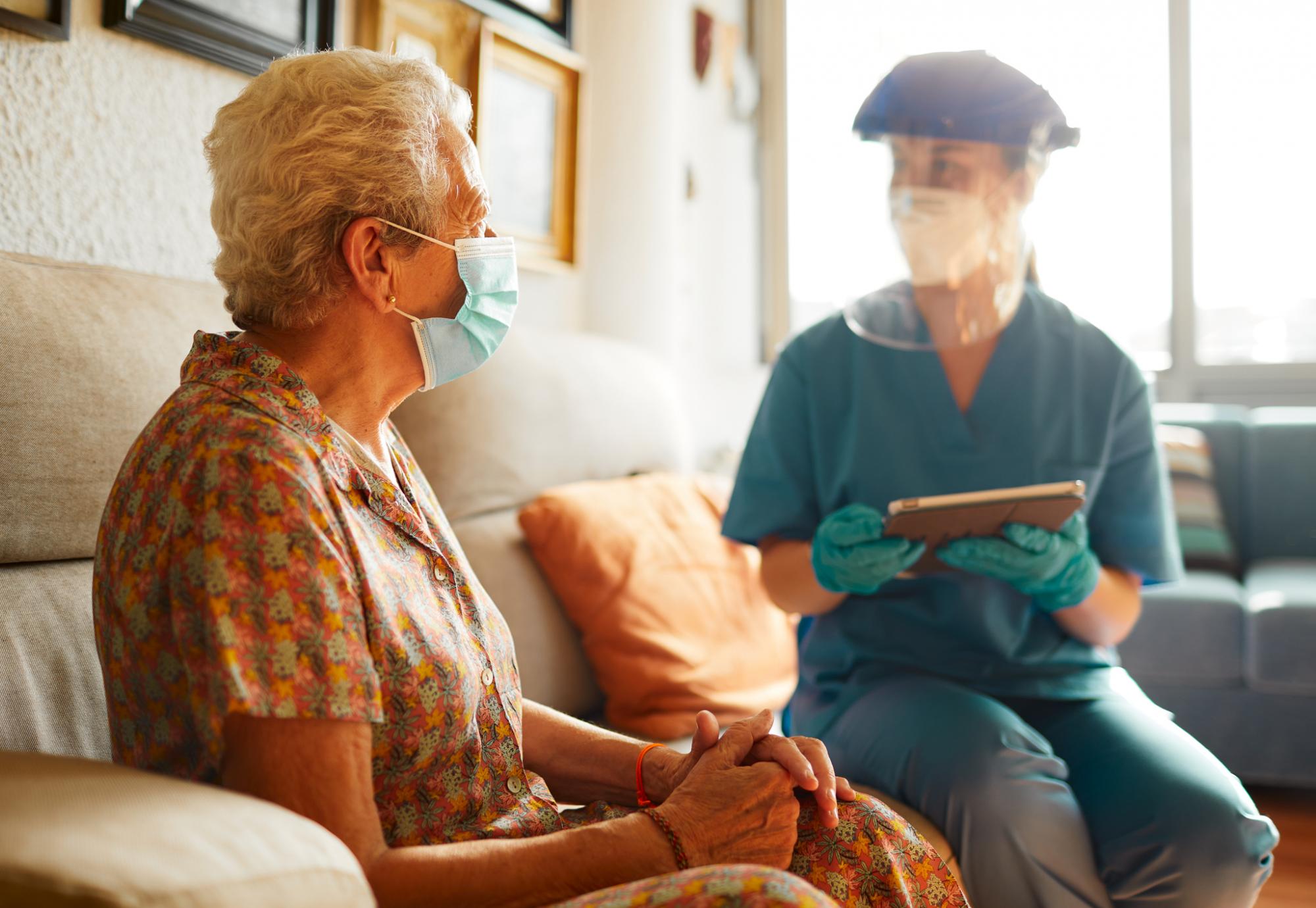 Elderly care home resident with a staff member in PPE