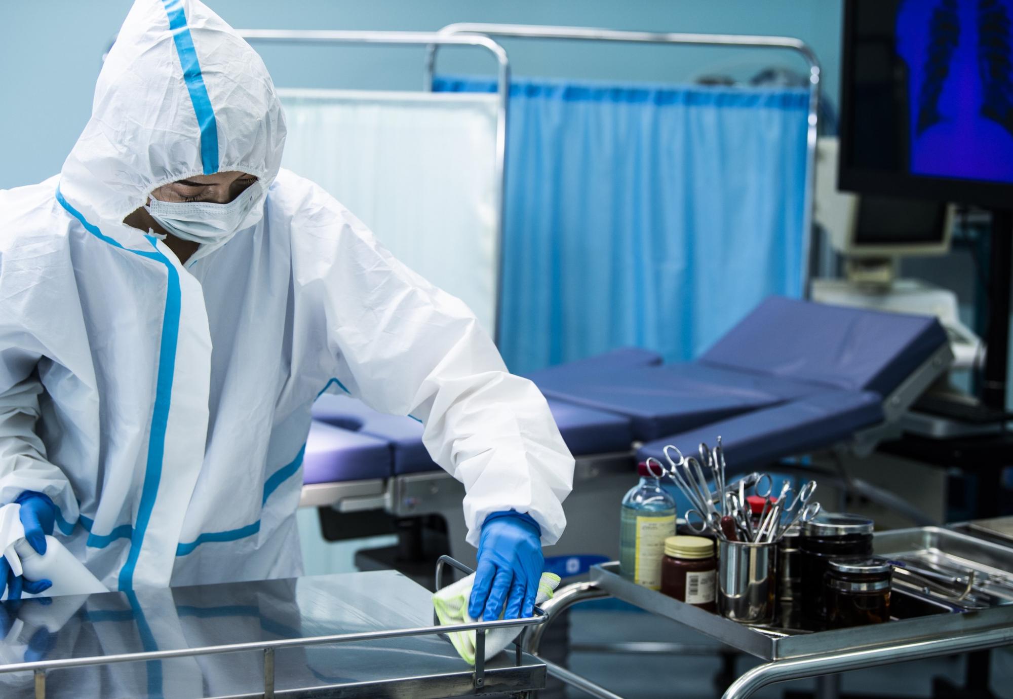 Individual in PPE wiping down a surgical surface