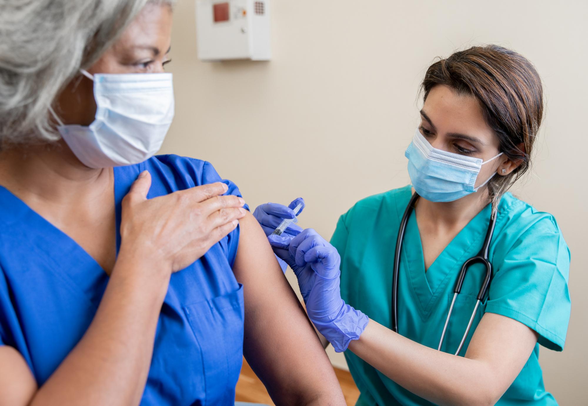 Nurse administering a vaccine to a colleague