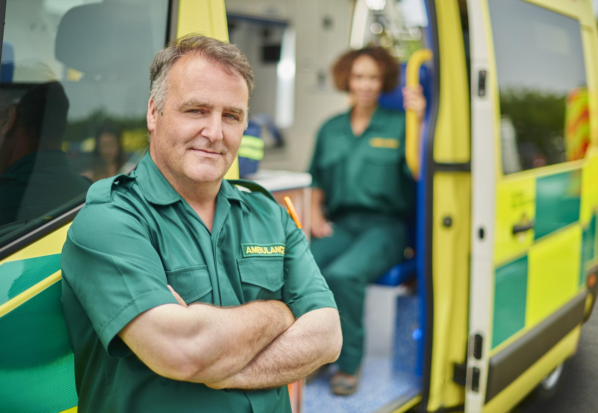 Ambulance driver stands outside his vehicle