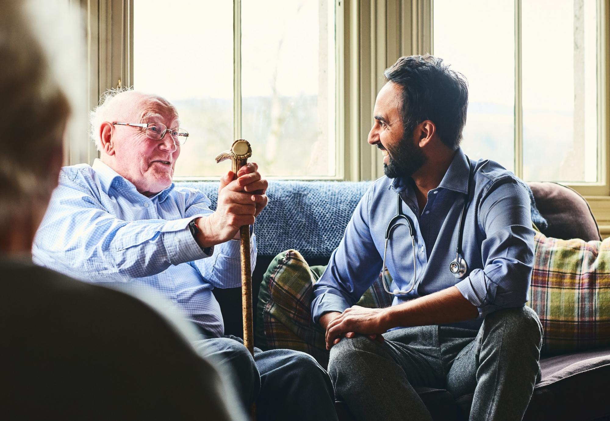 Elderly man with a cane talking with a male doctor