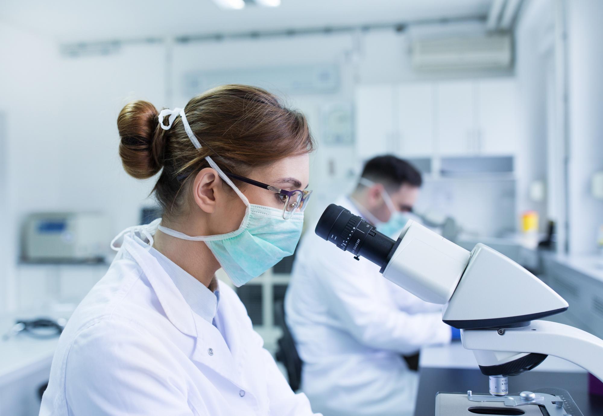 Scientists using a microscope in a lab