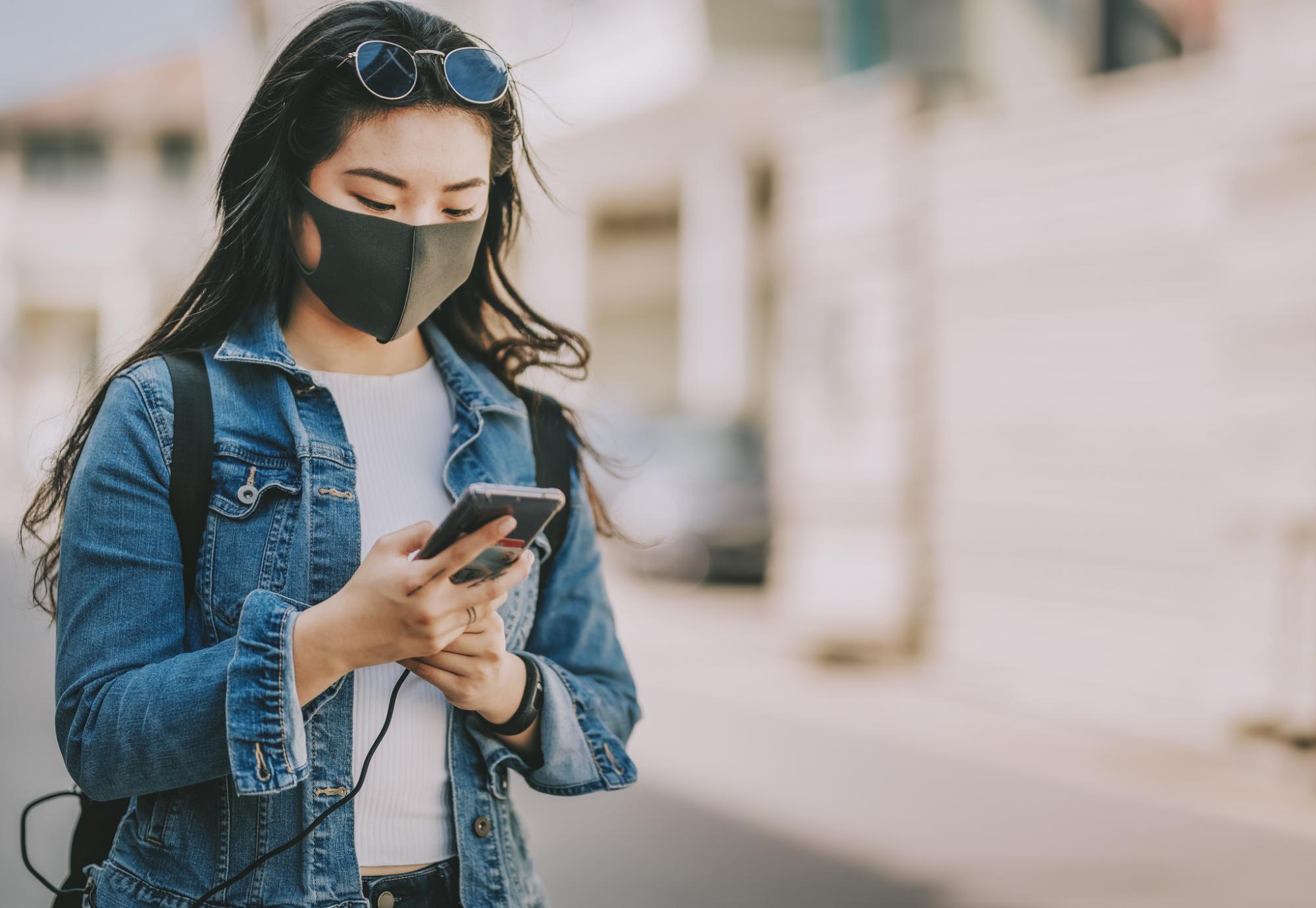 Young woman with a face mask using her phone