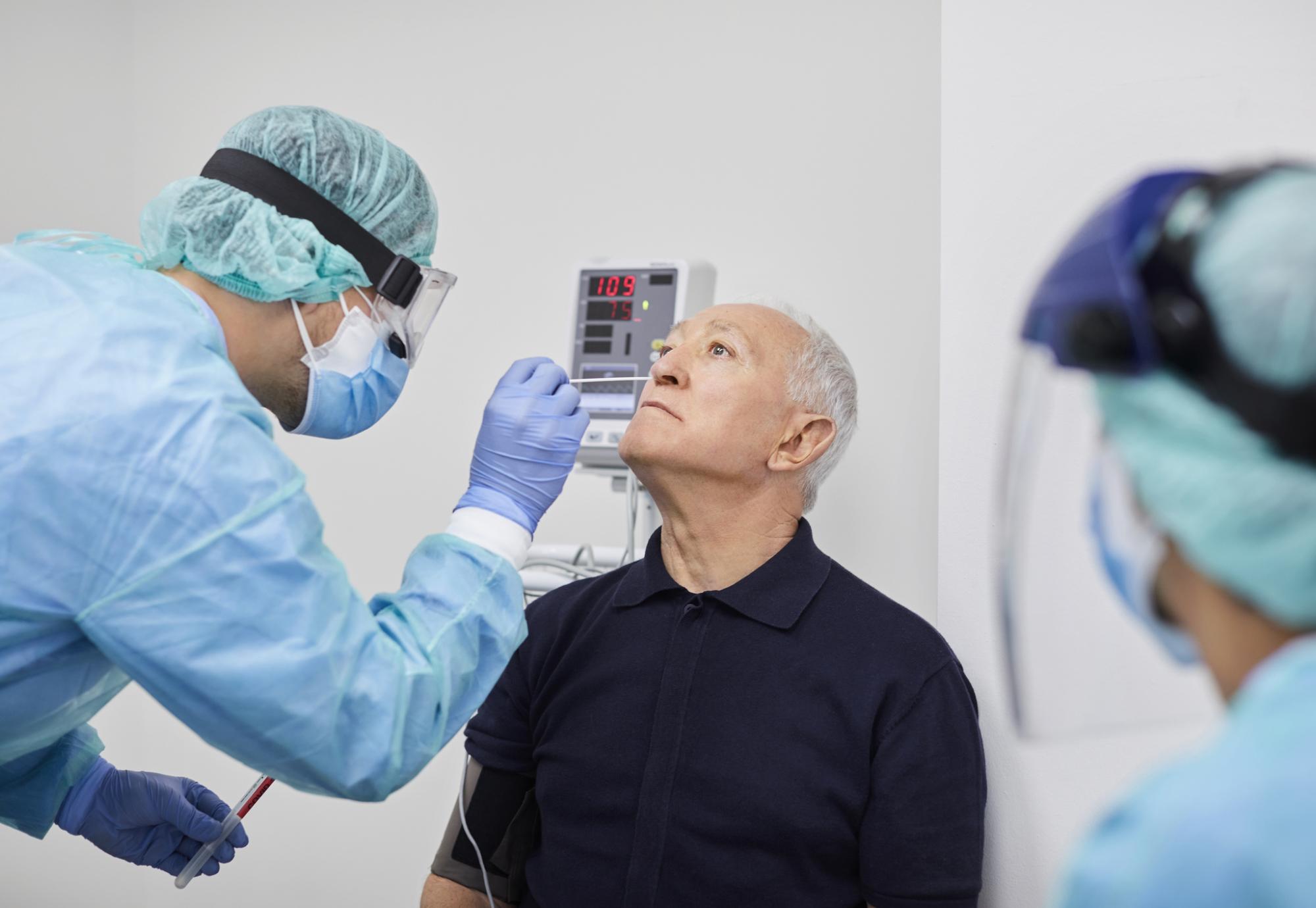 Medical professional performing a Covid test on an elderly patient