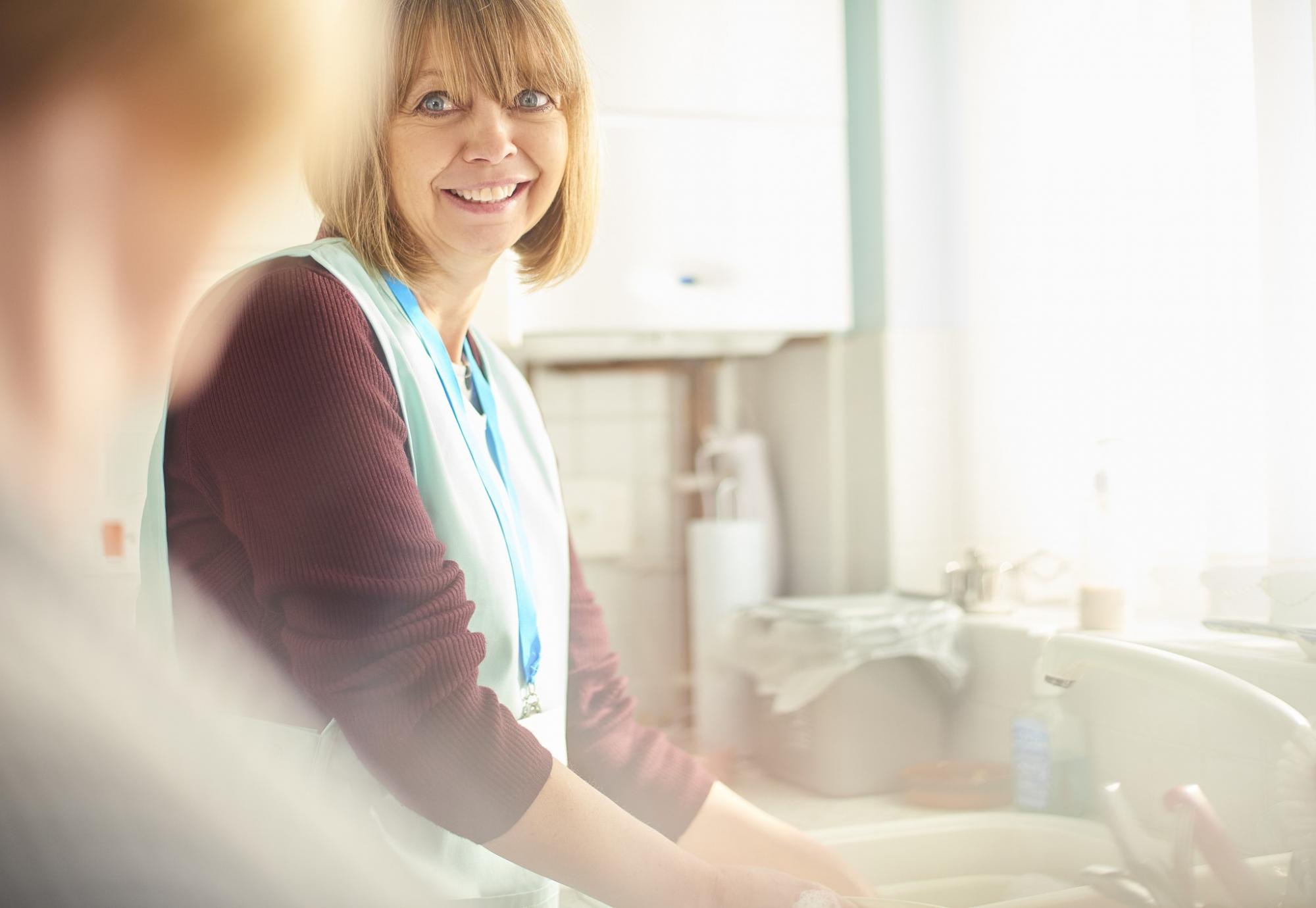 Social care worker washing dishes