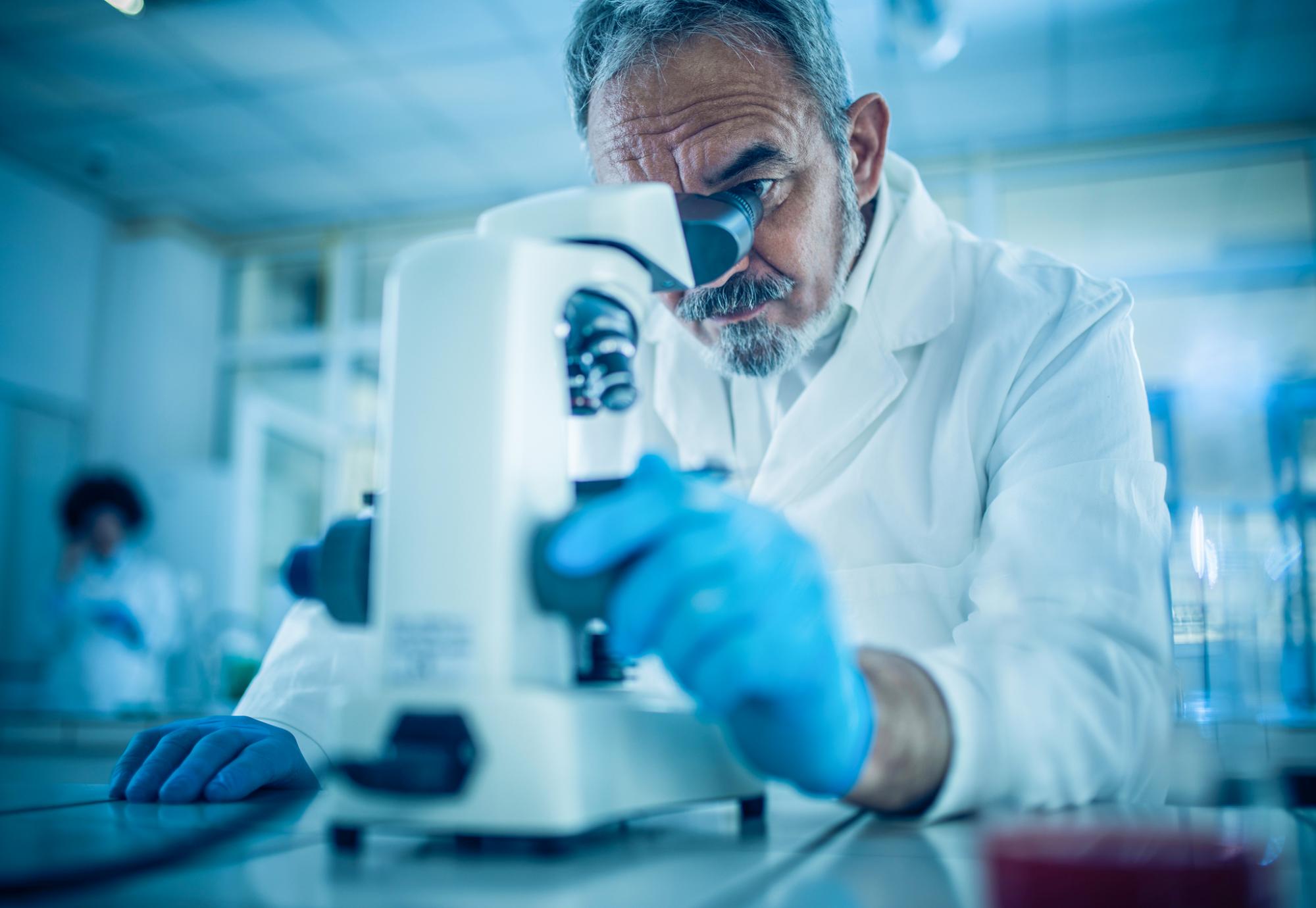 Researcher looking down a microscope