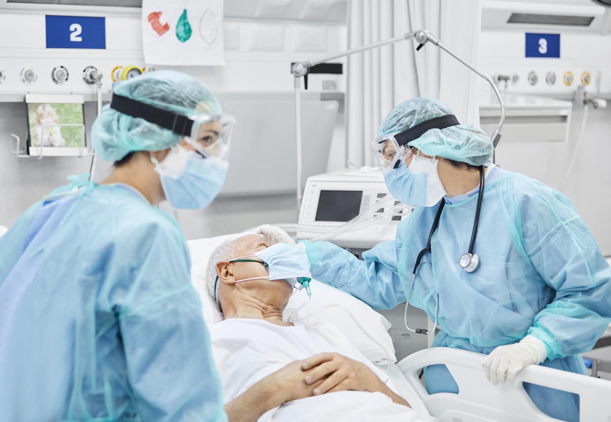 Patient in a hospital bed being treated by two members of staff