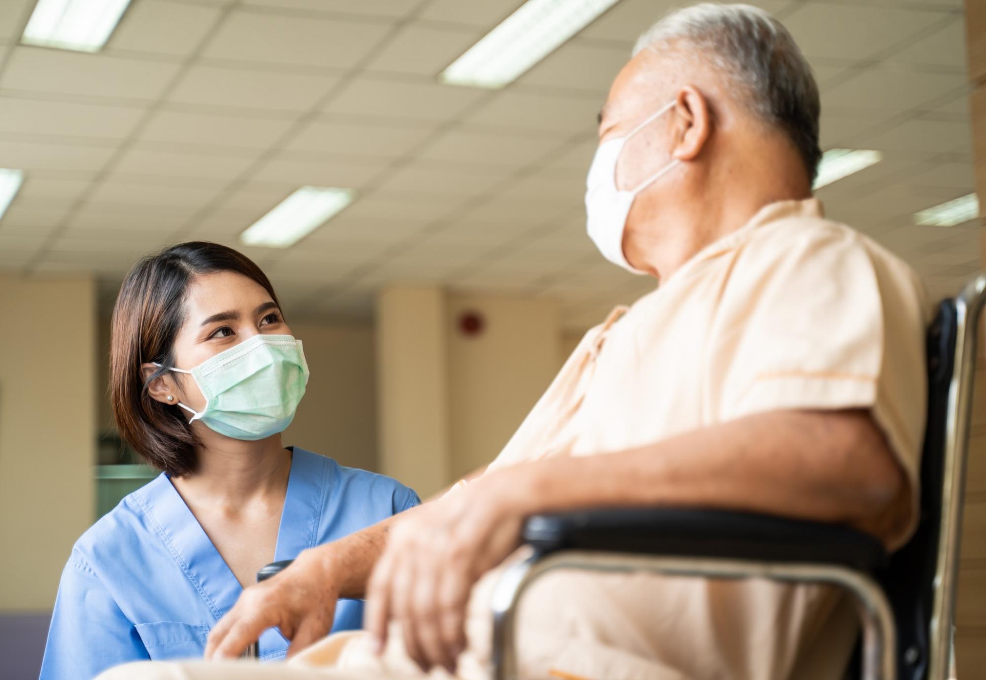 Nurse stood by patient in a wheelchair talking