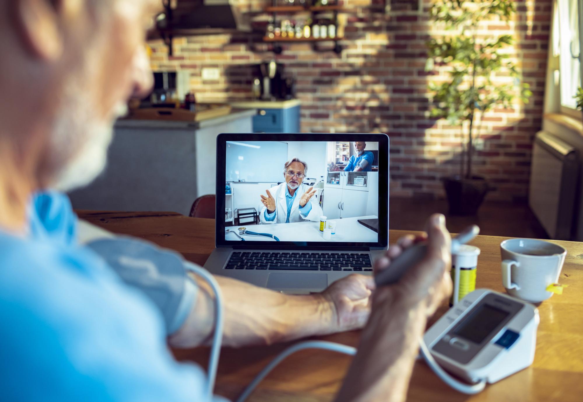 Doctor using remote video consultation with a patient taking their blood pressure