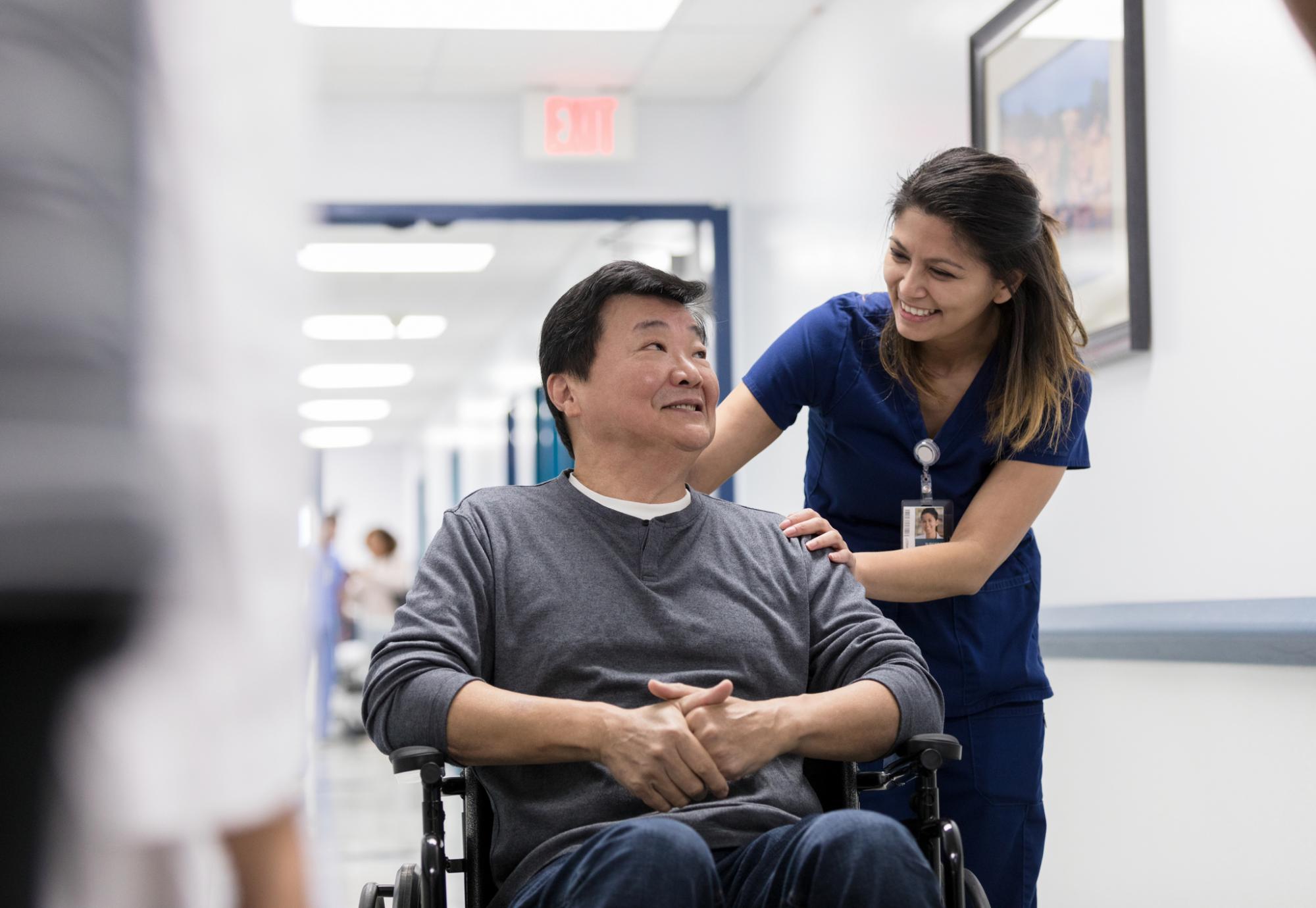 Hospital staff member pushes patient through corridor