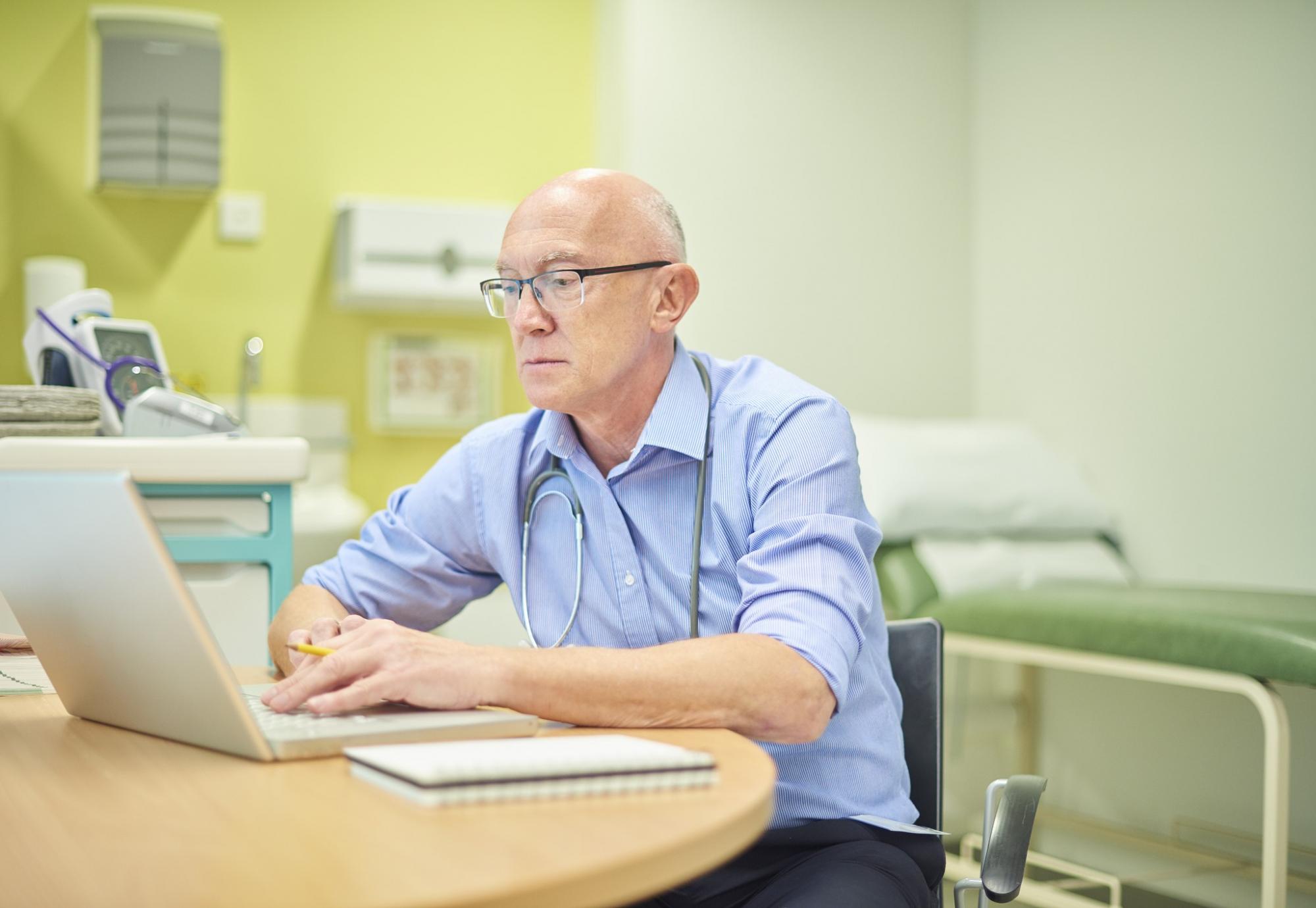 Doctor using a laptop in his practice room