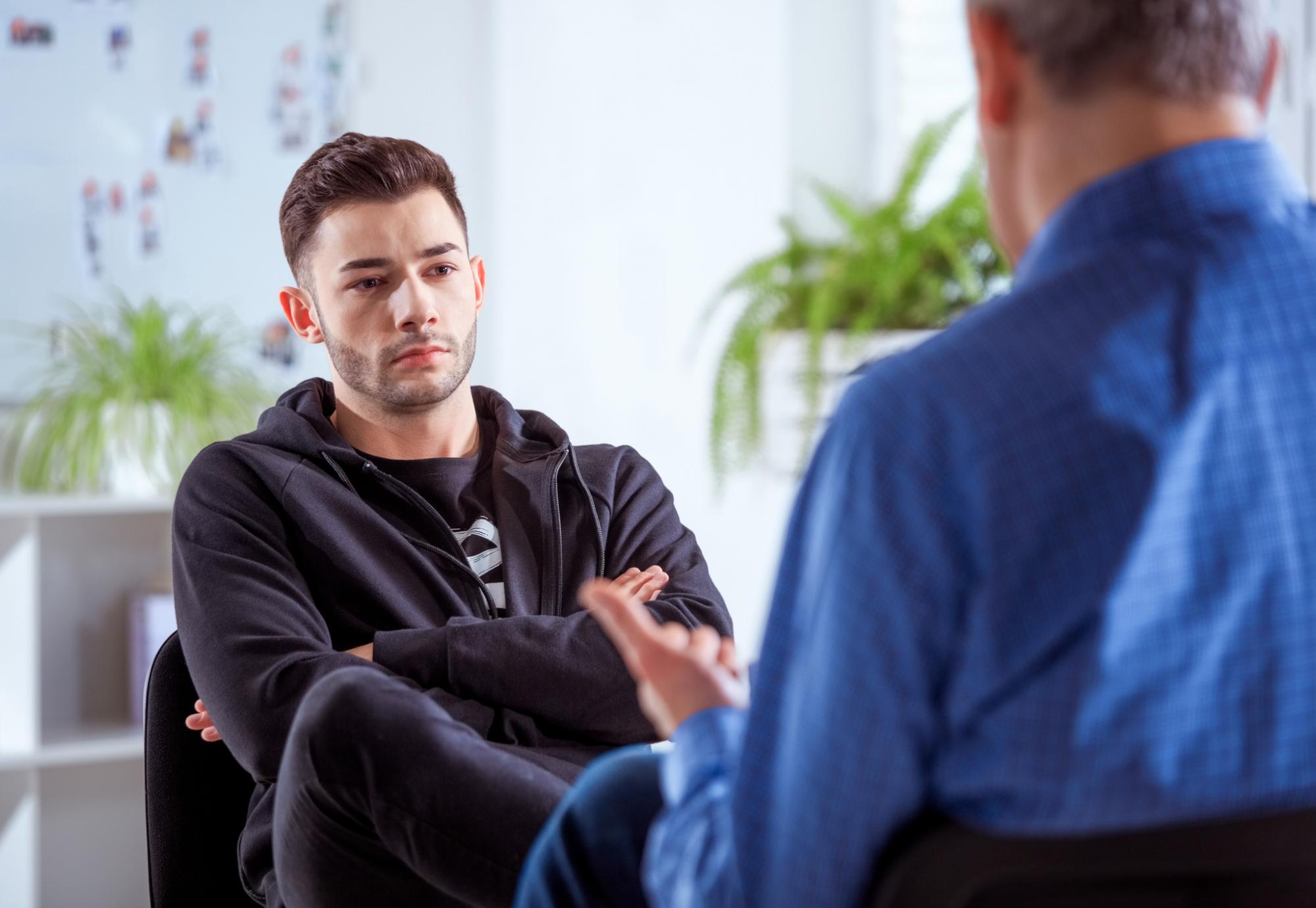 Young withdrawn man talking to a professional