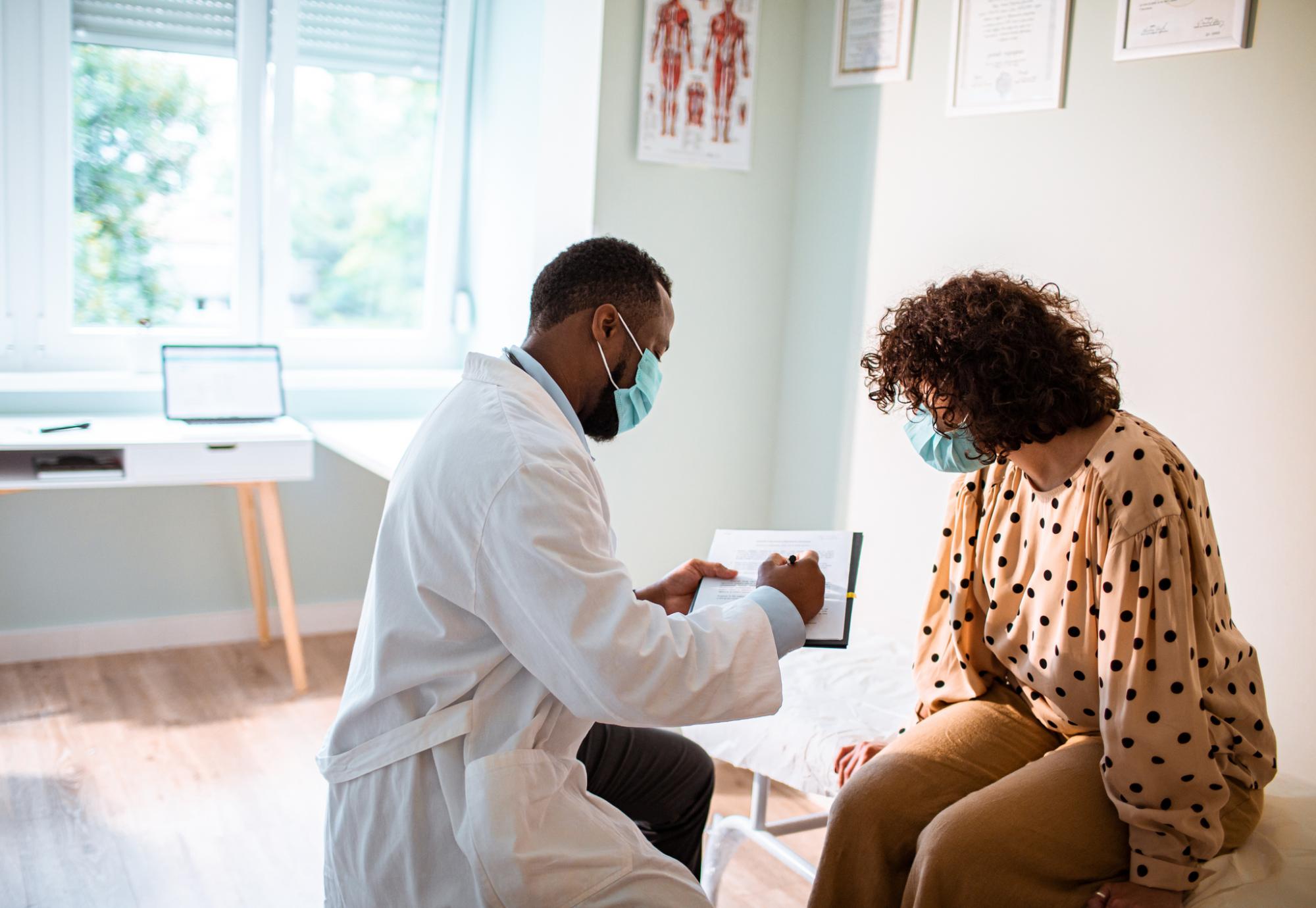 GP wearing a mask seeing to a patient