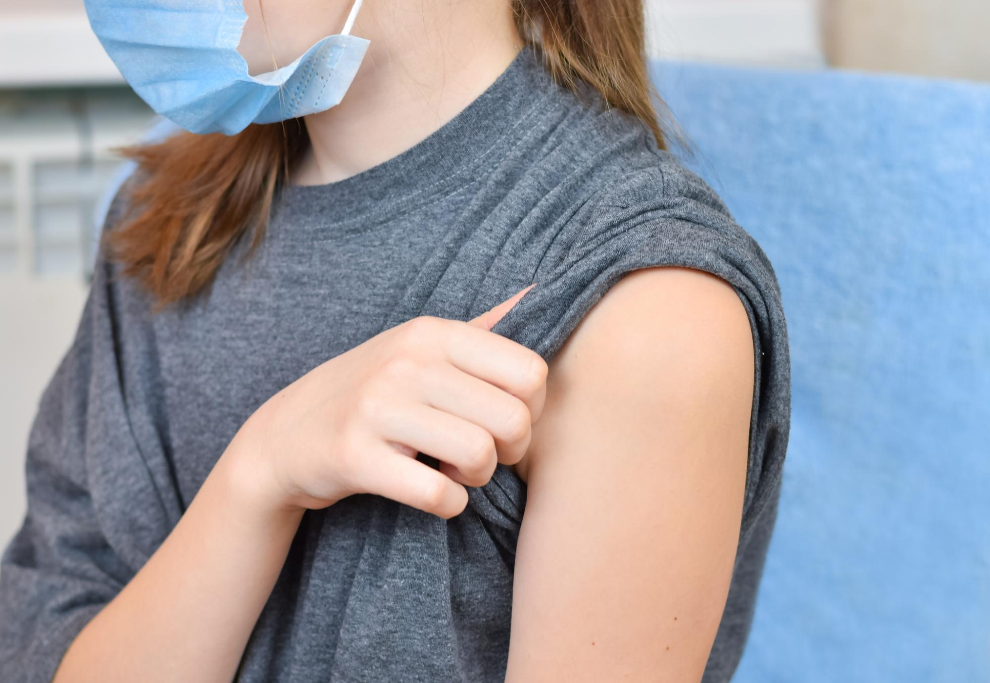Young girl rolling up her sleeve ahead of vaccine