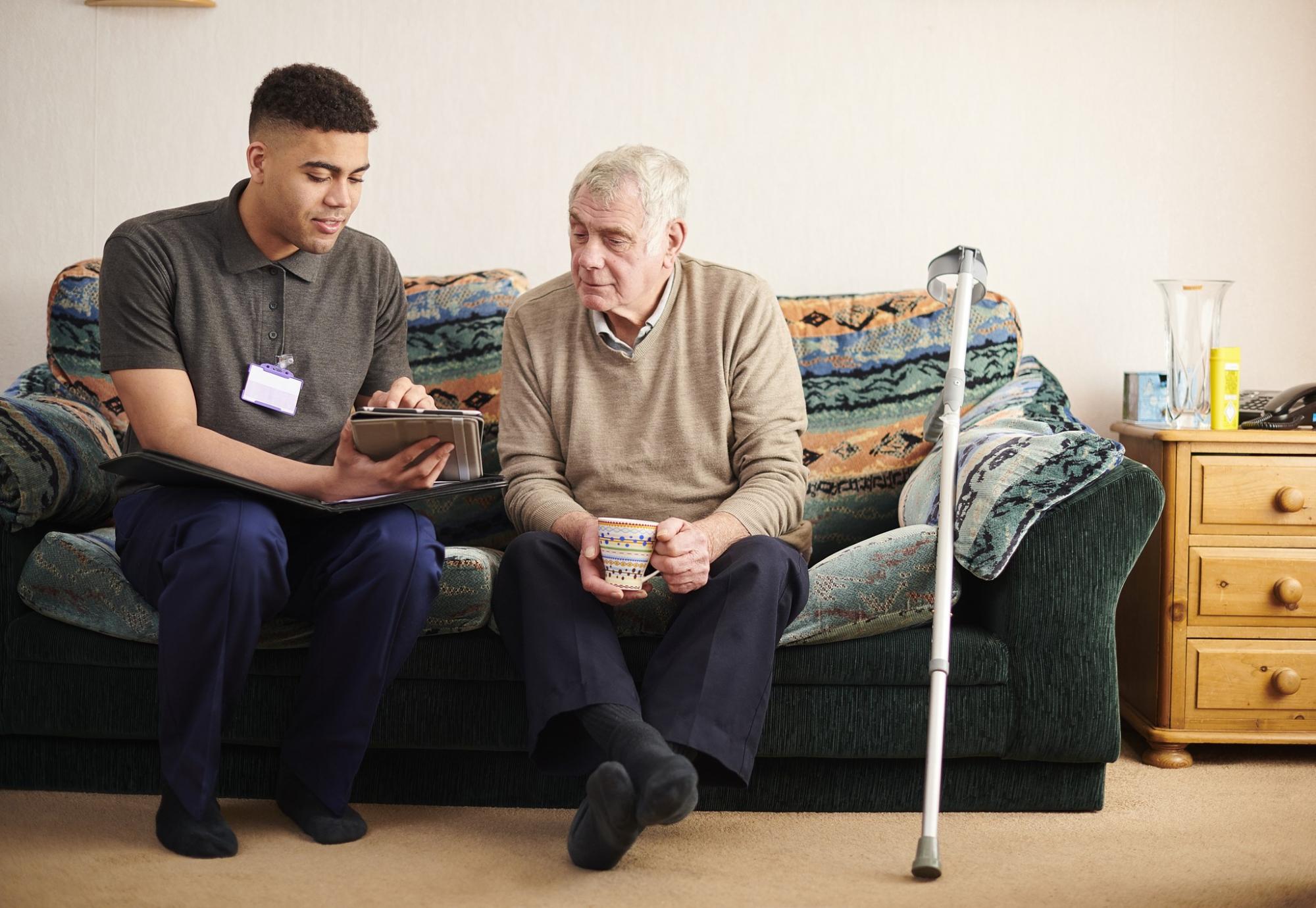 Social care worker supporting an elderly male patient