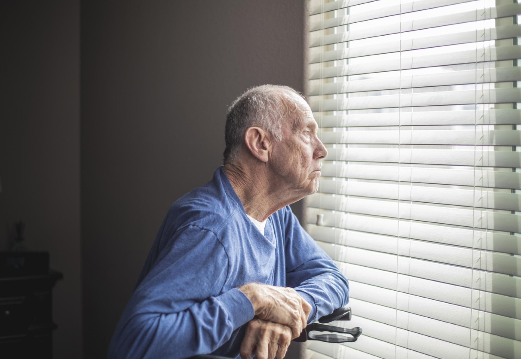 elderly man looking out window 