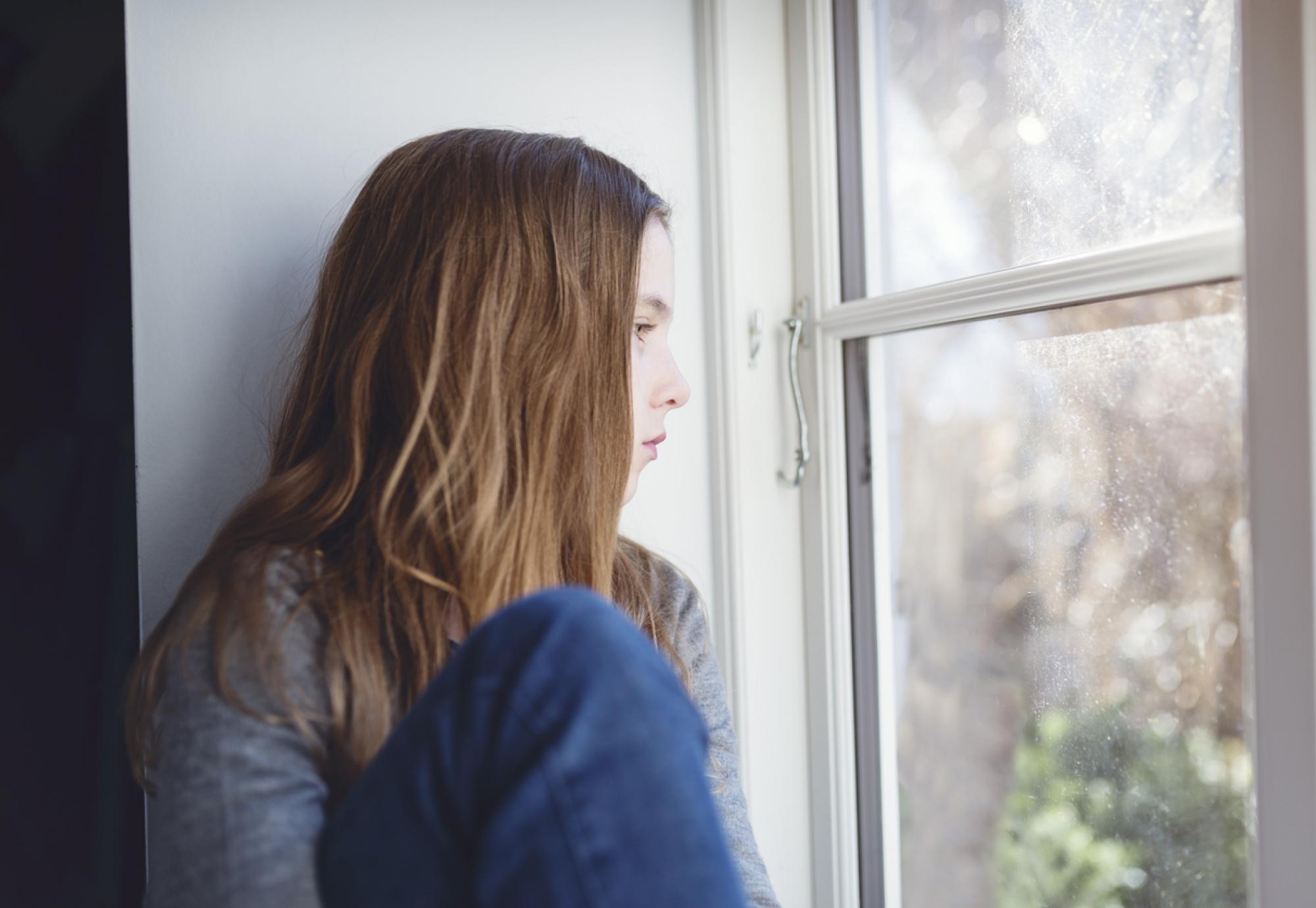 young girl looking out window