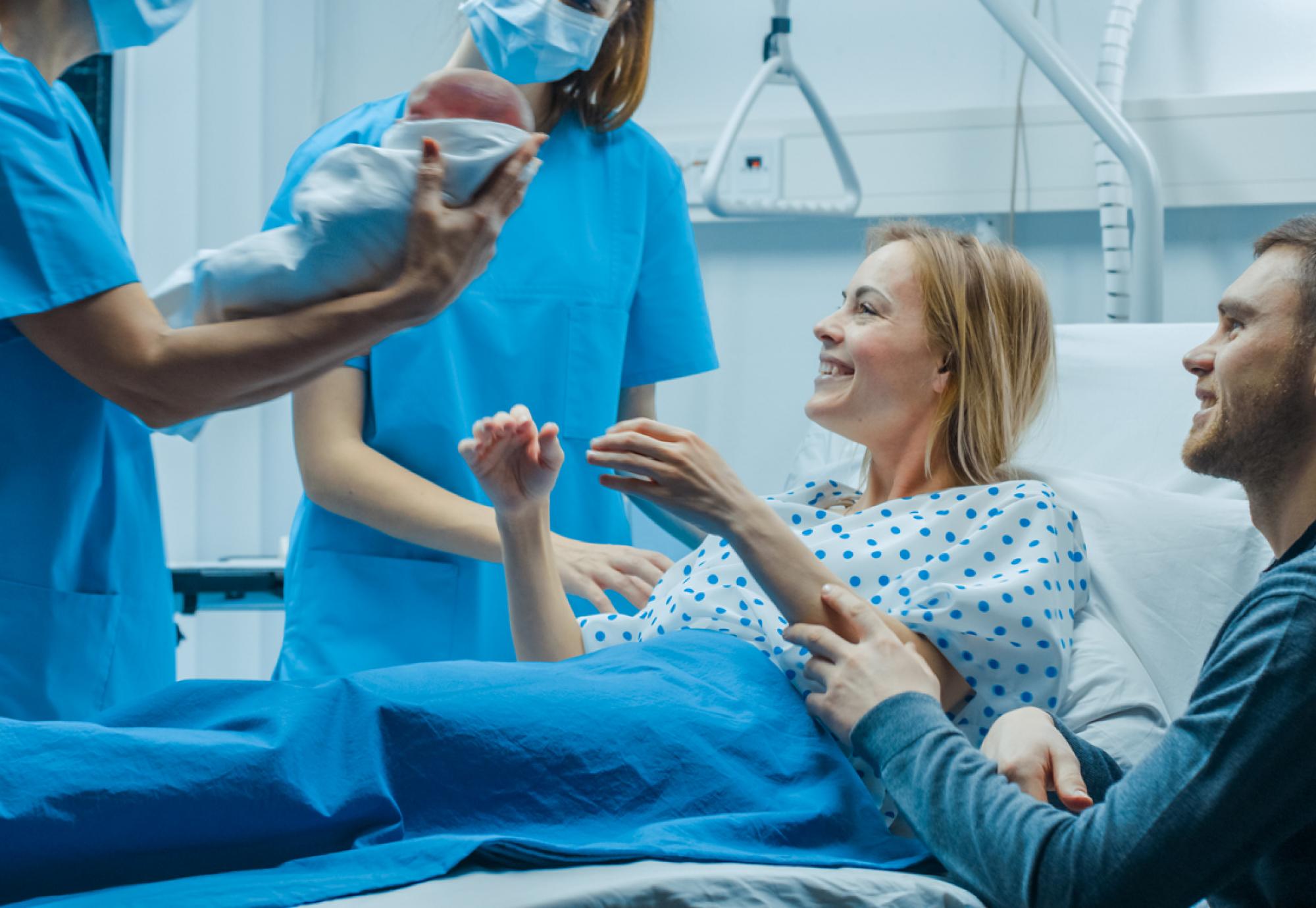 Midwife giving baby to mother