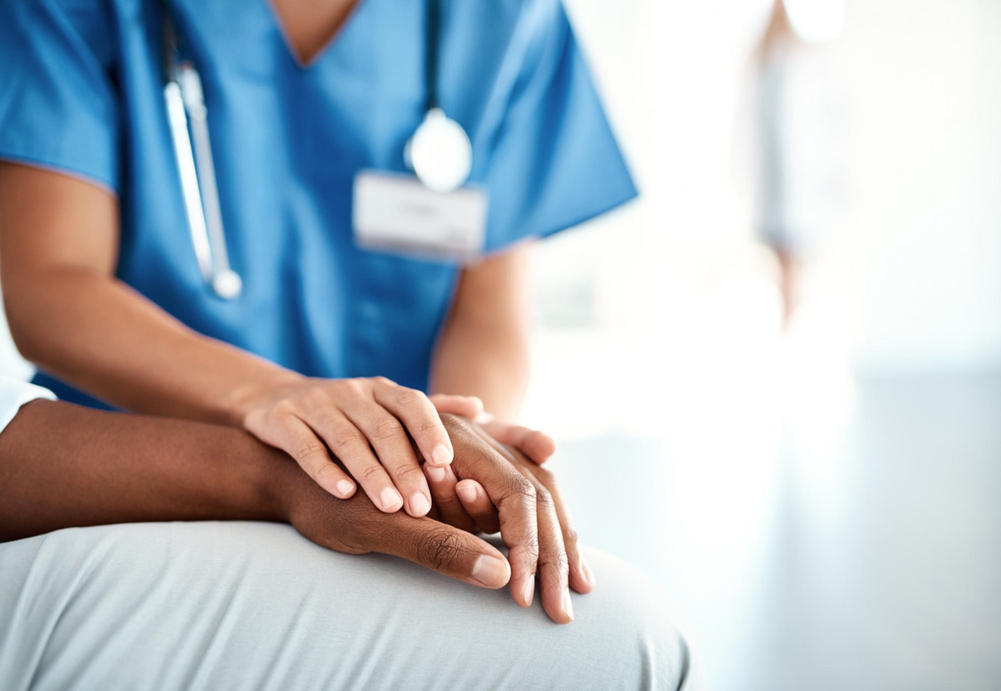 Nurses comforting patient with their hand