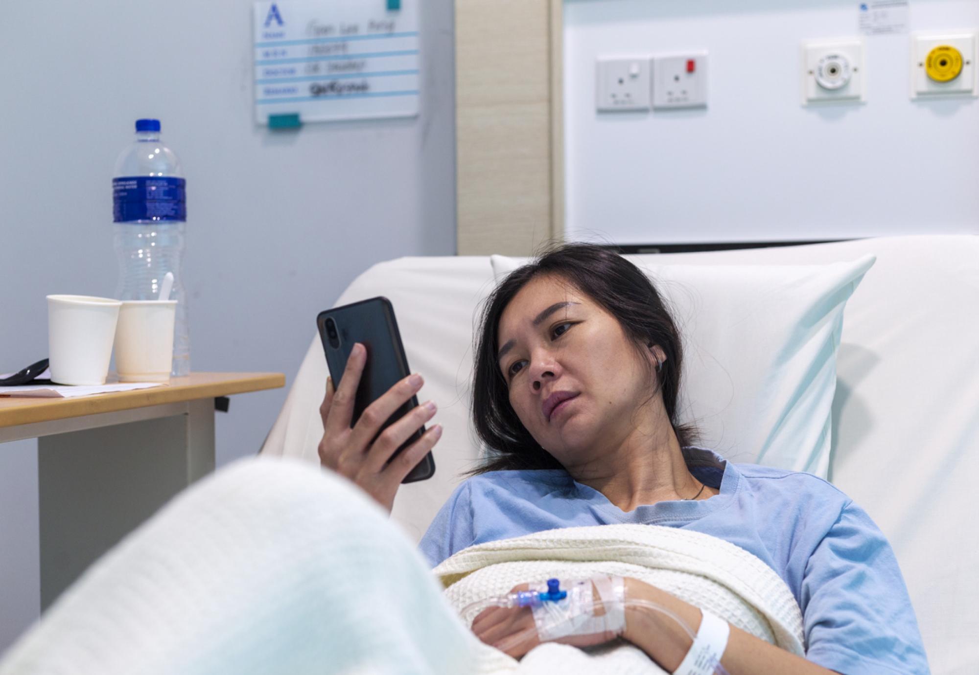 Female patient in bed on her phone