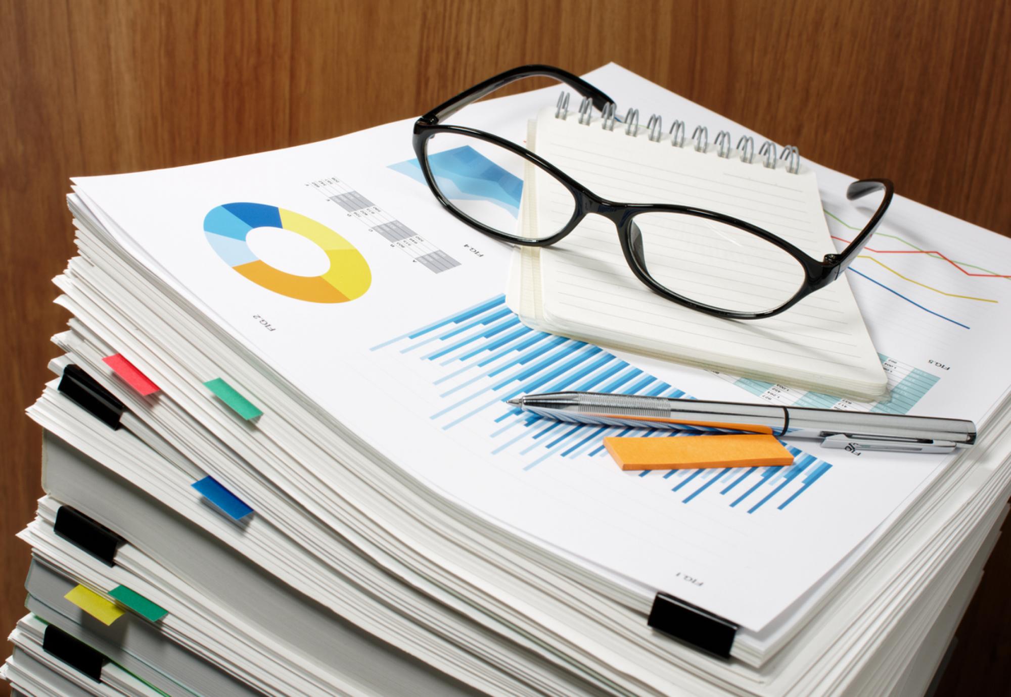 Glasses and pens on top of a stack of documents