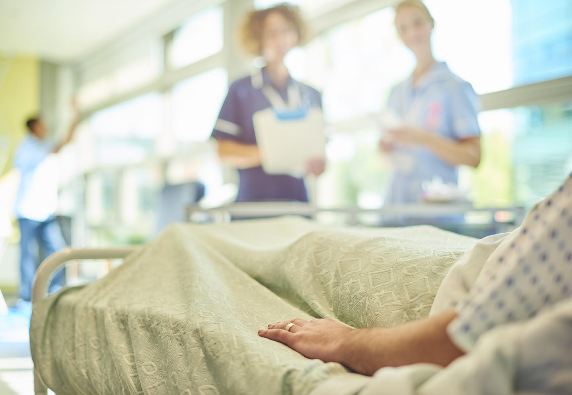 Patient in bed speaking to two nurses