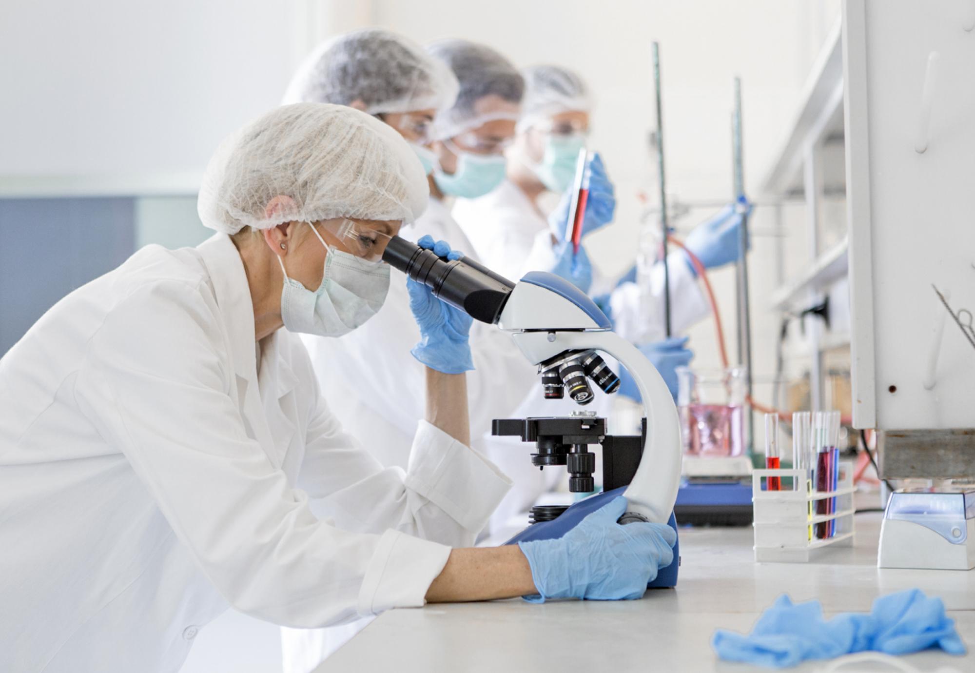 Scientists studying a virus by looking through a microscope