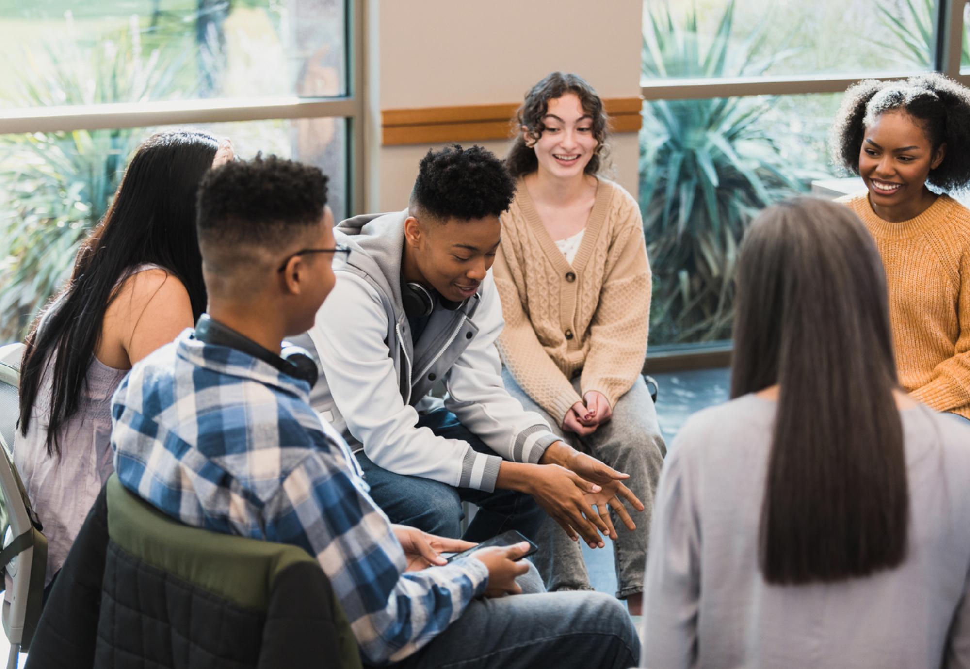 Group of young people sat in a circle talking