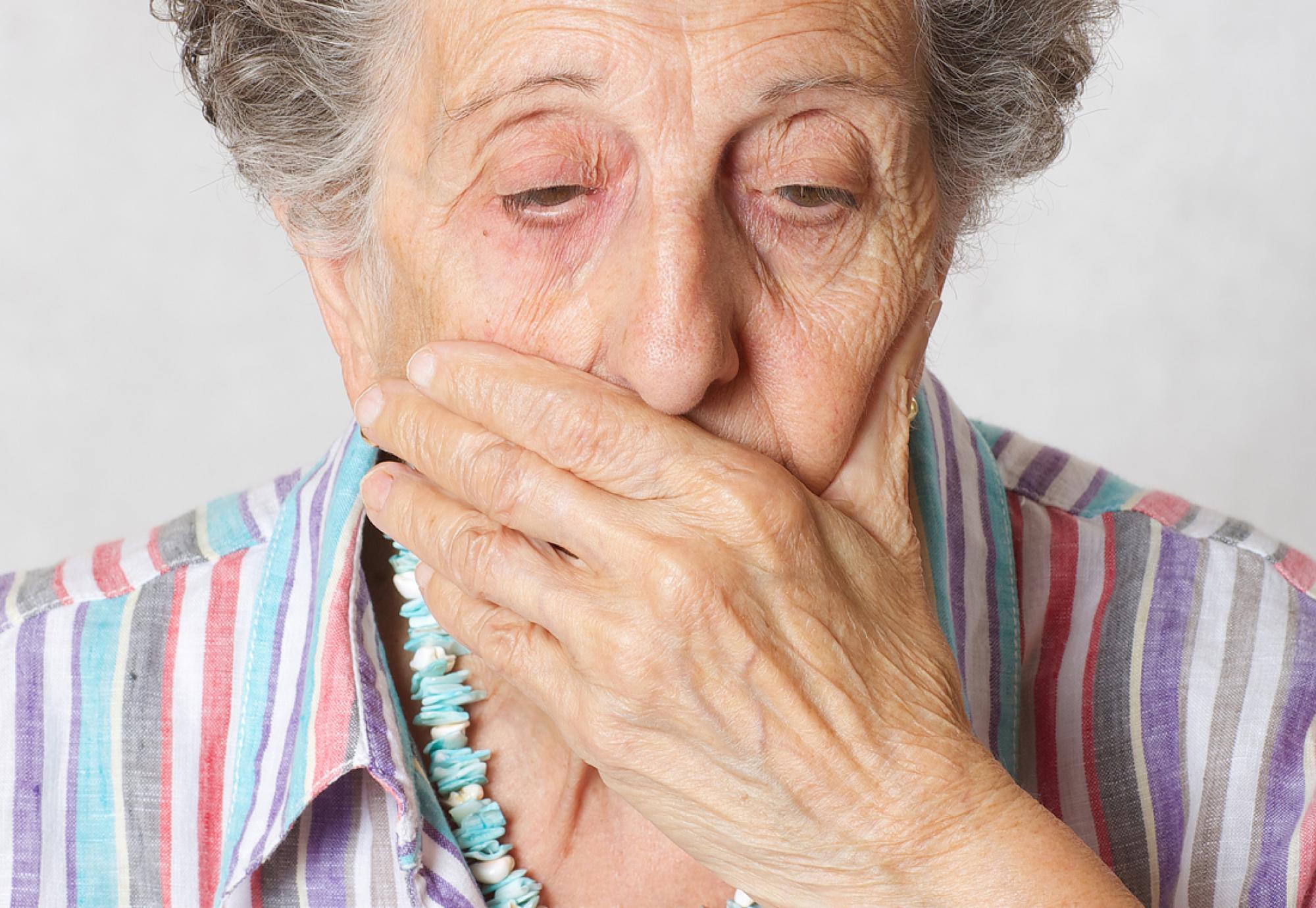 Senior woman with a hand over her mouth