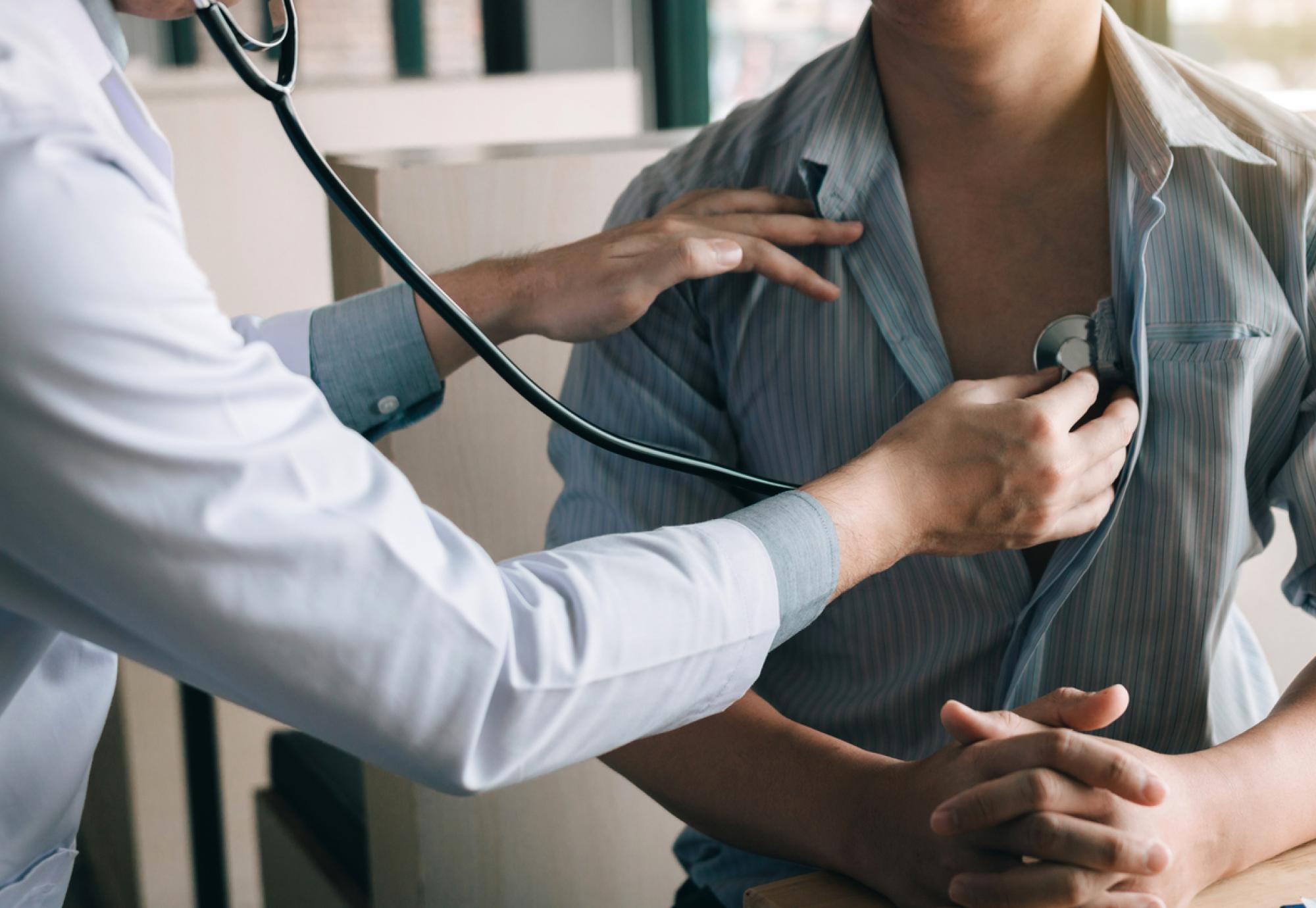 Doctor using stethoscope to check patient's heartbeat