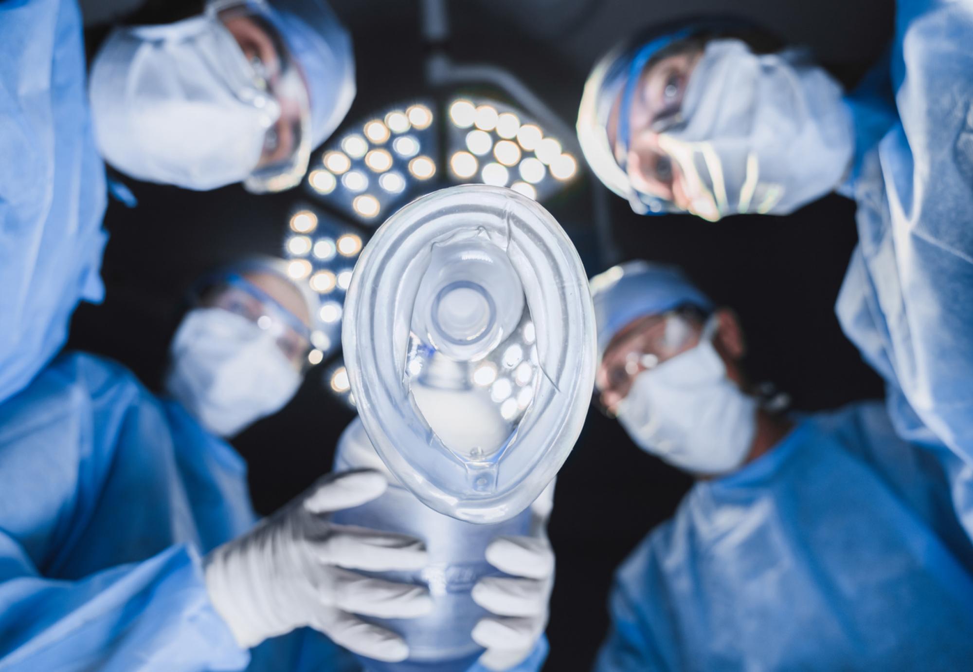 Anesthetist holding oxygen mask above patient in surgery room