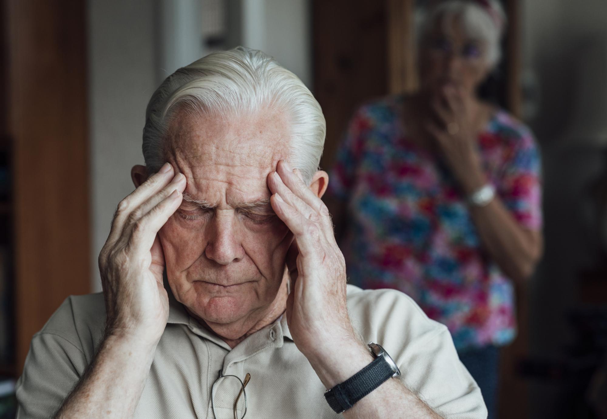 Woman looking at man holding his head