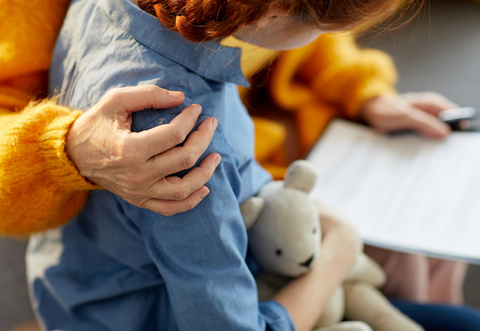 Adult's arm over the shoulder of a child