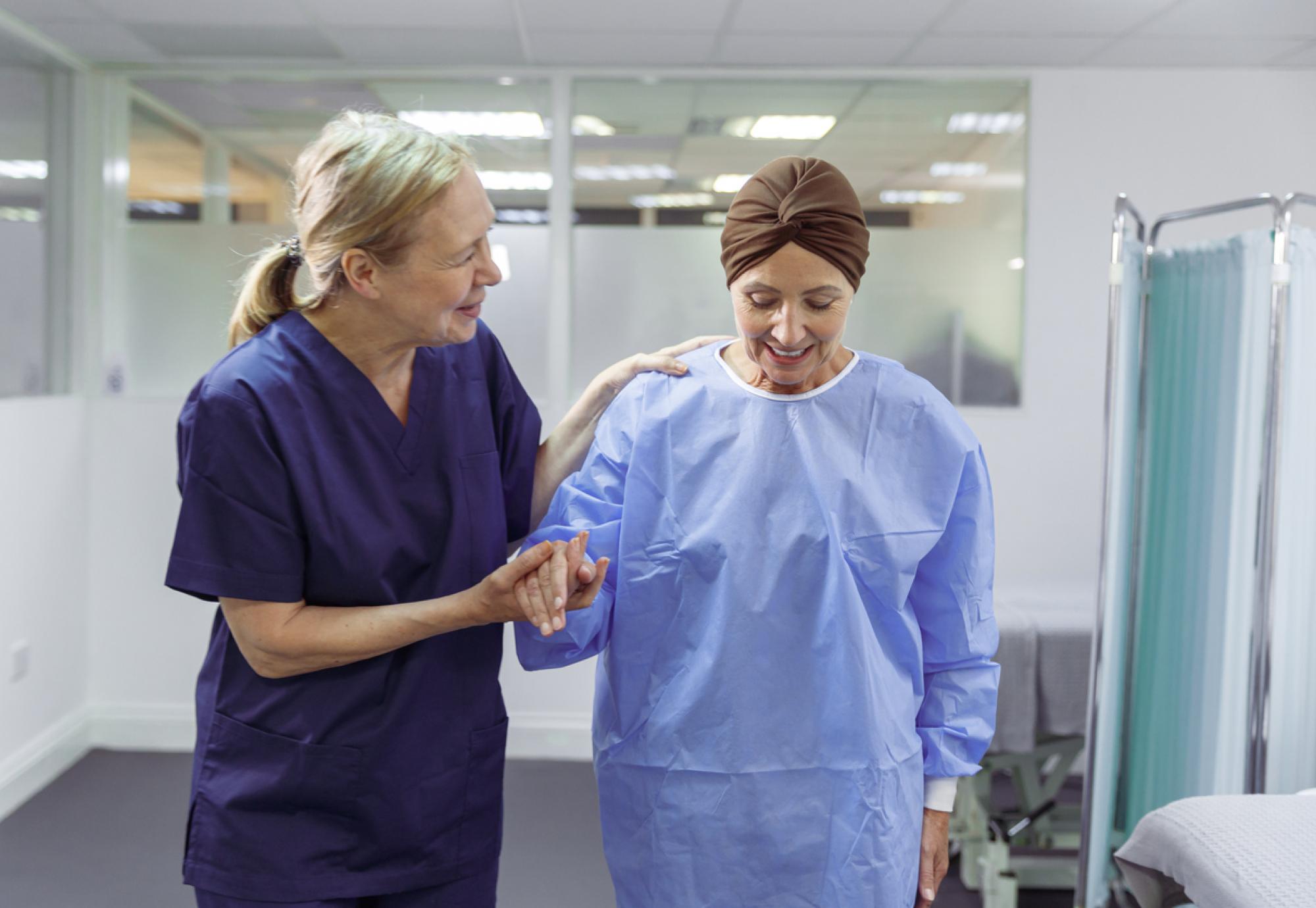 urse assisting female cancer patient walk through hospital ward 