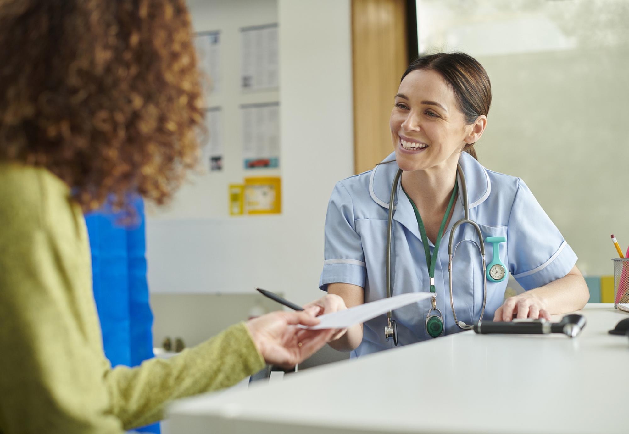 Happy nurse giving patient an advice note