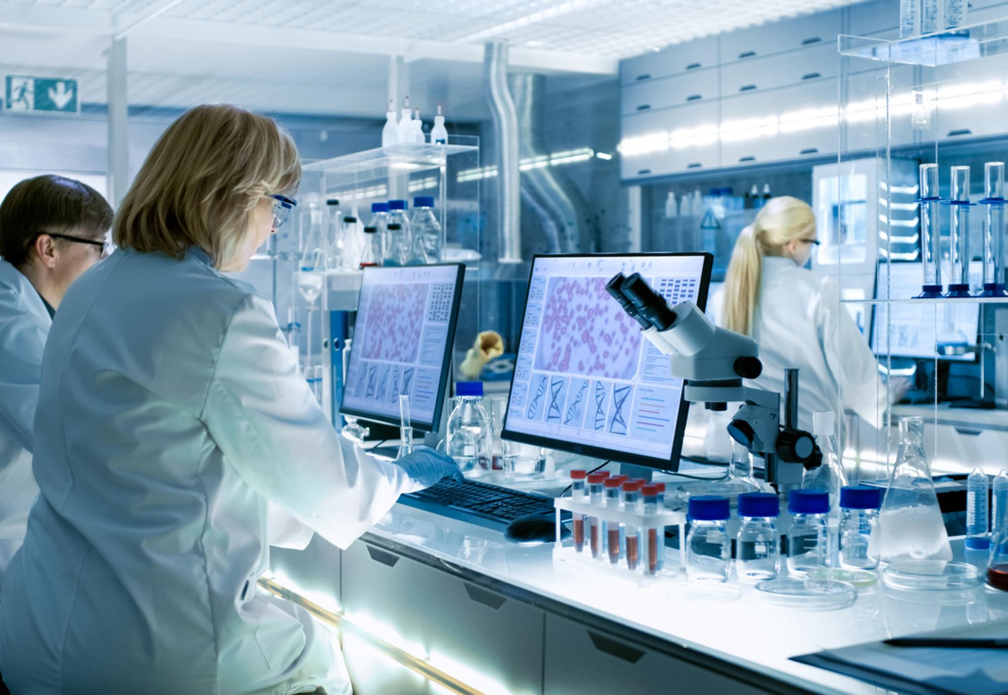 Female and Male Scientists Working on their Computers In A Big Modern Laboratory