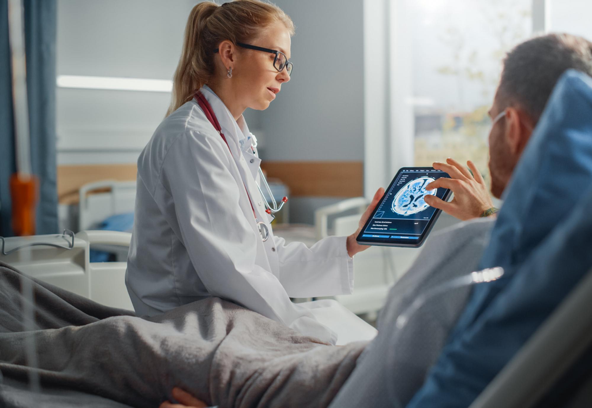 Female health professional tends to male patient on hospital ward