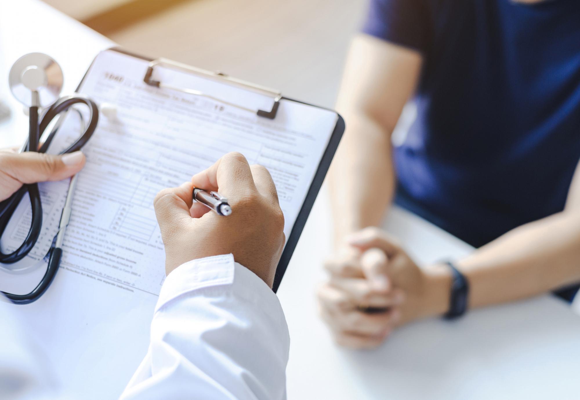 Close-up of a male doctor hand hold a silver pen and showing pad in hospital