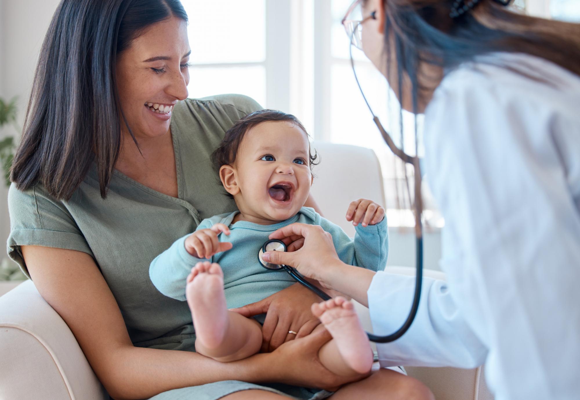 Shot of a baby sitting on her mother's lap while being examined by a doctor