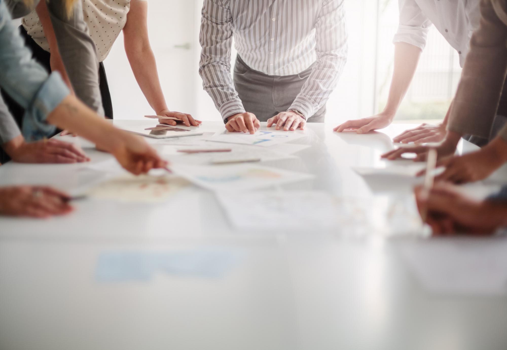 Group of professionals standing around a table brainstorming ideas 