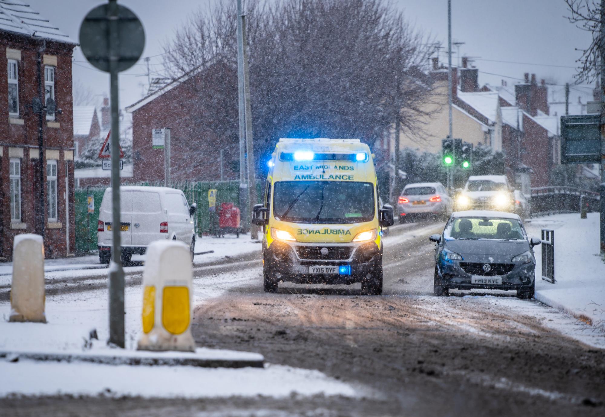 Ambulance driving through snow depicting the NHS winter pressures