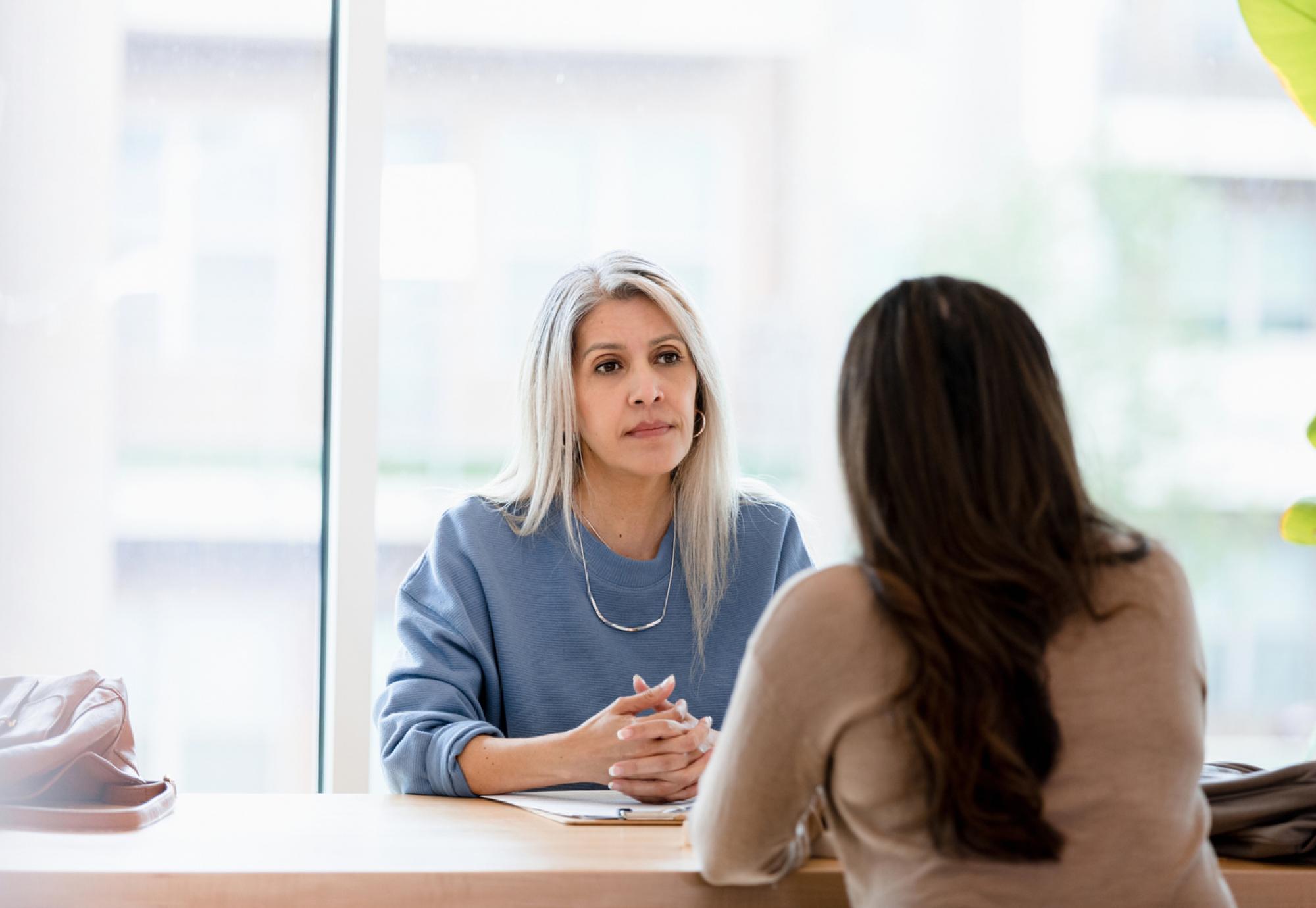 Woman talking to a serious businesswoman depicting how endometriosis affects people in the workplace and women's health