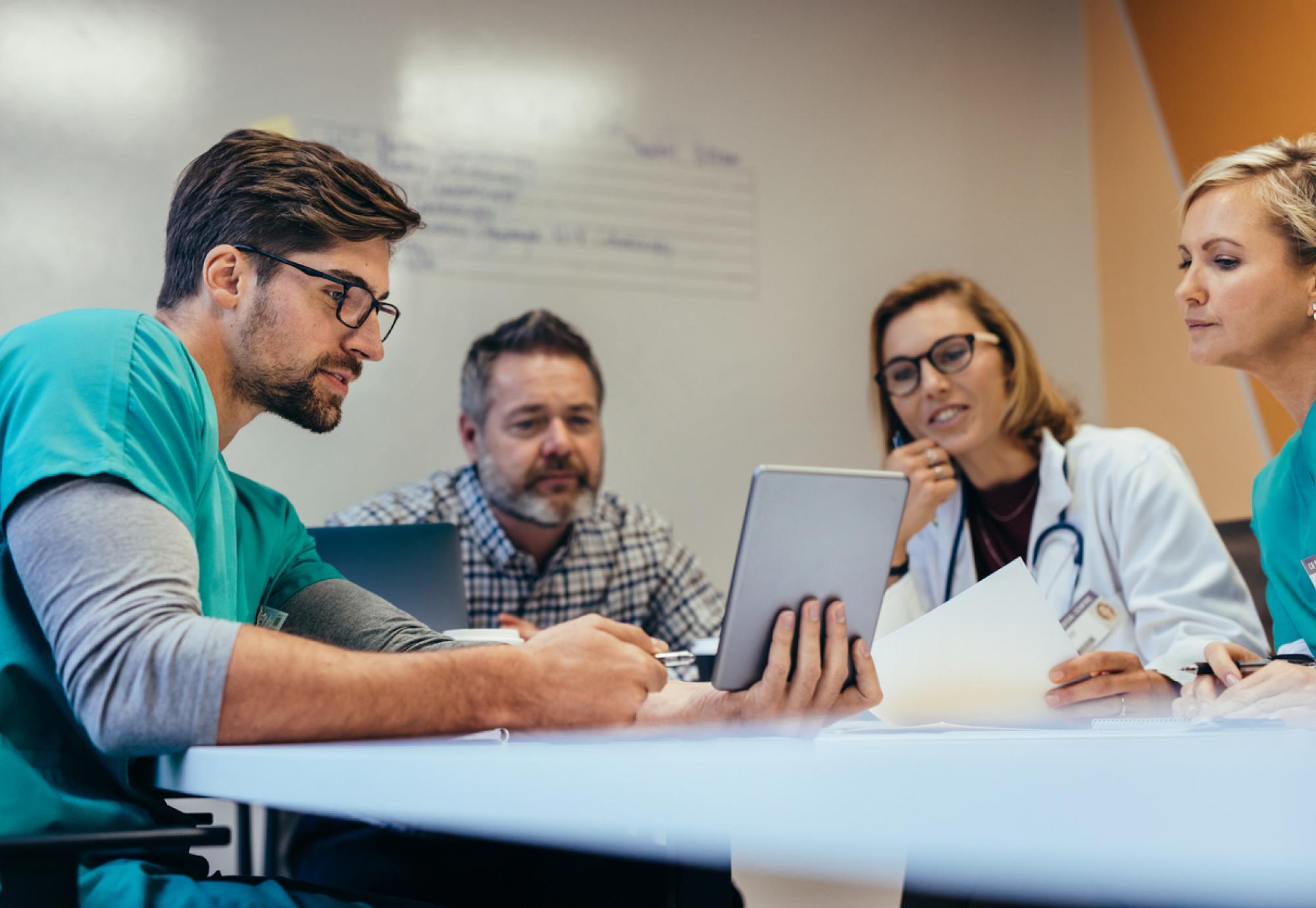 Group of health professionals talking around a table depicting the national conversation on the future of healthcare in Wales