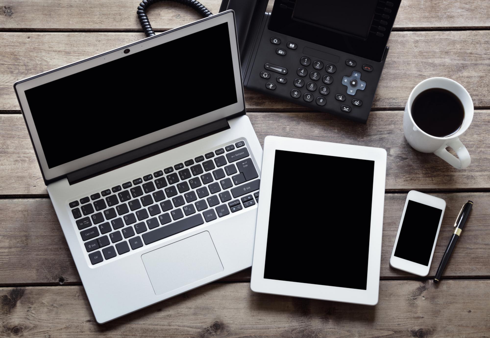 Overhead image of a laptop, tablet and phone depicting the NHS technology sector