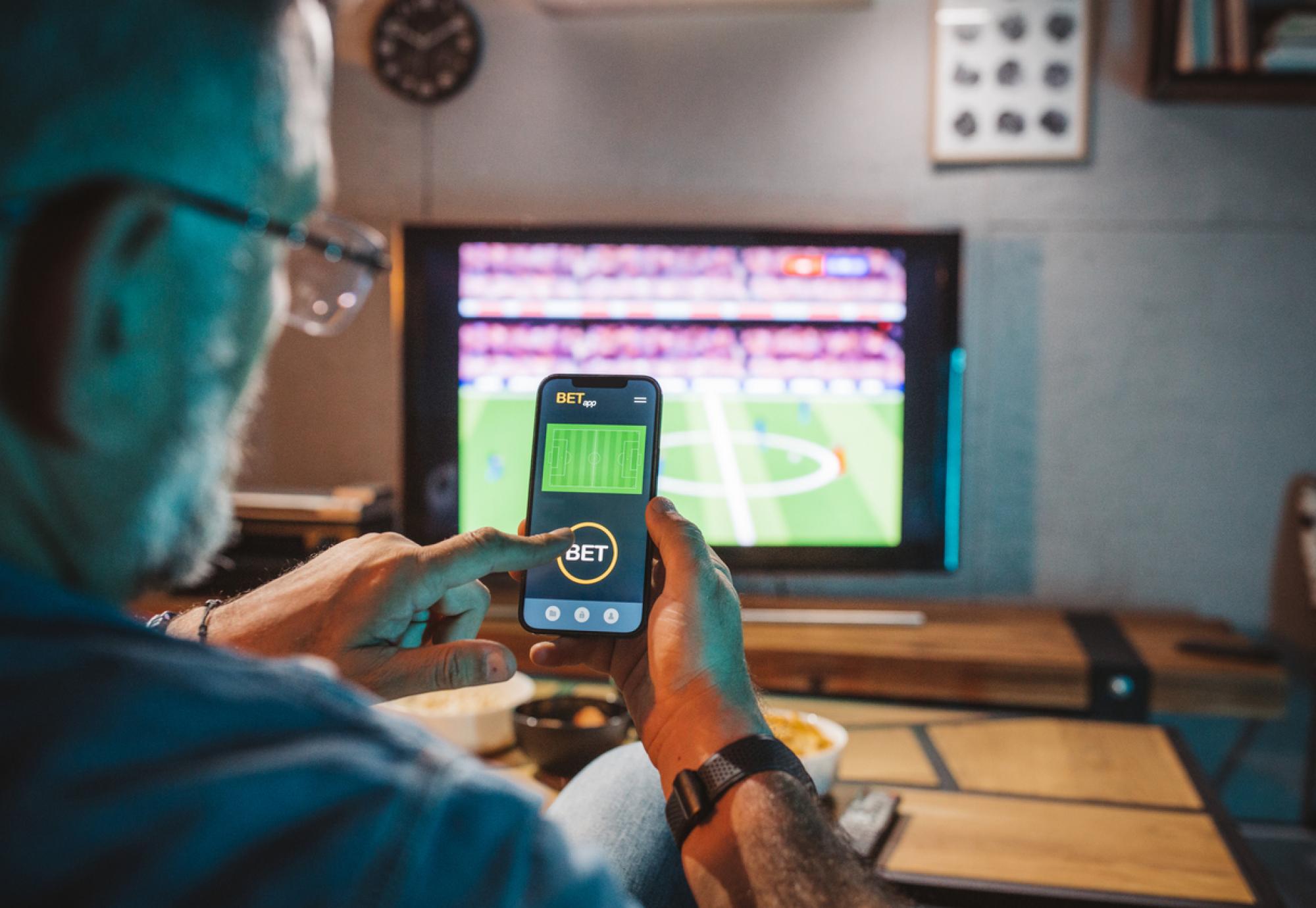 Man gambling on a football game on his phone